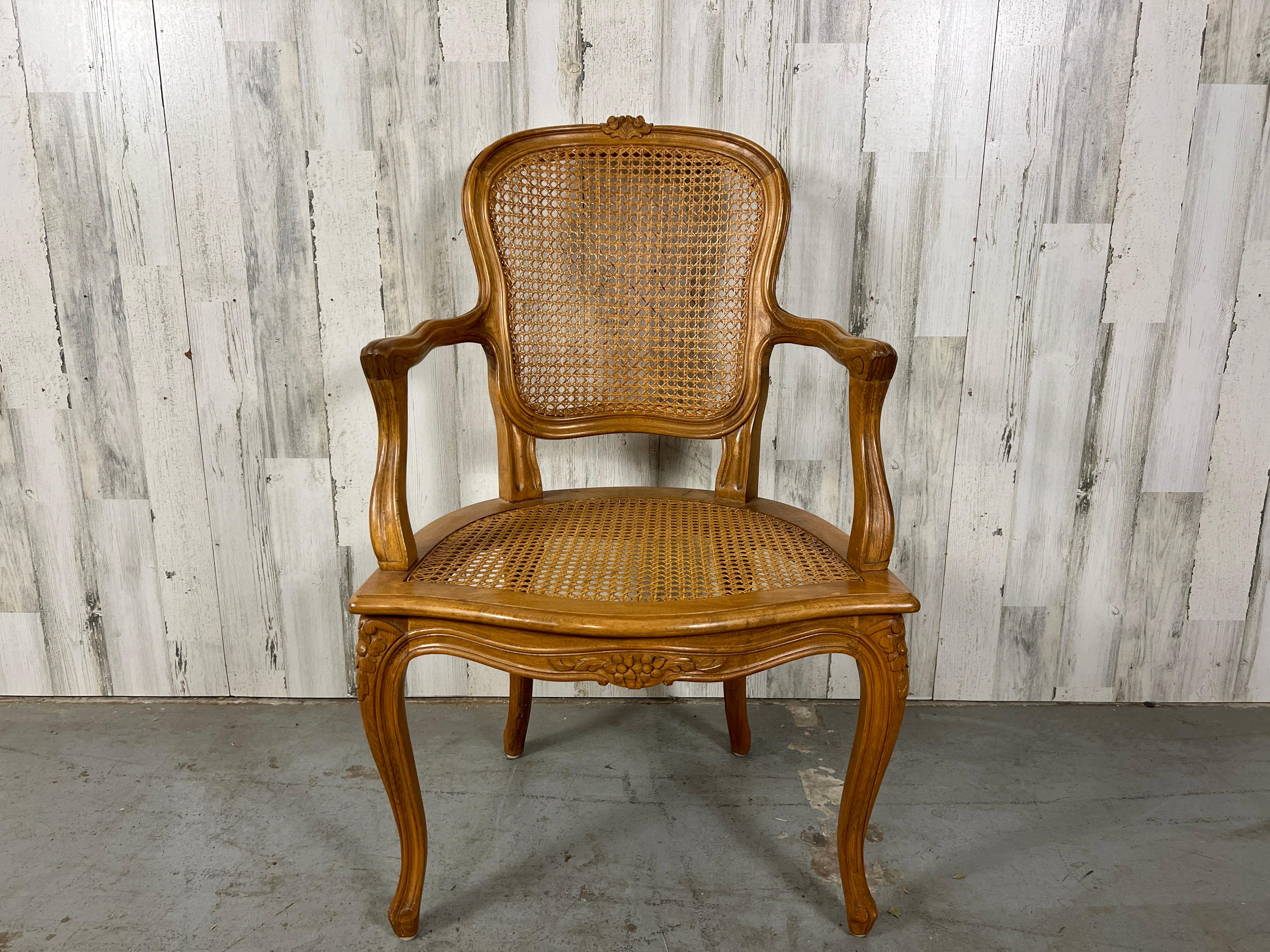 Very elegant sculptural cane armchair with carved floral accents. The curved back makes this very more comfortable than a straight back chair. Can be used as a desk chair, dining chair or hall chair.