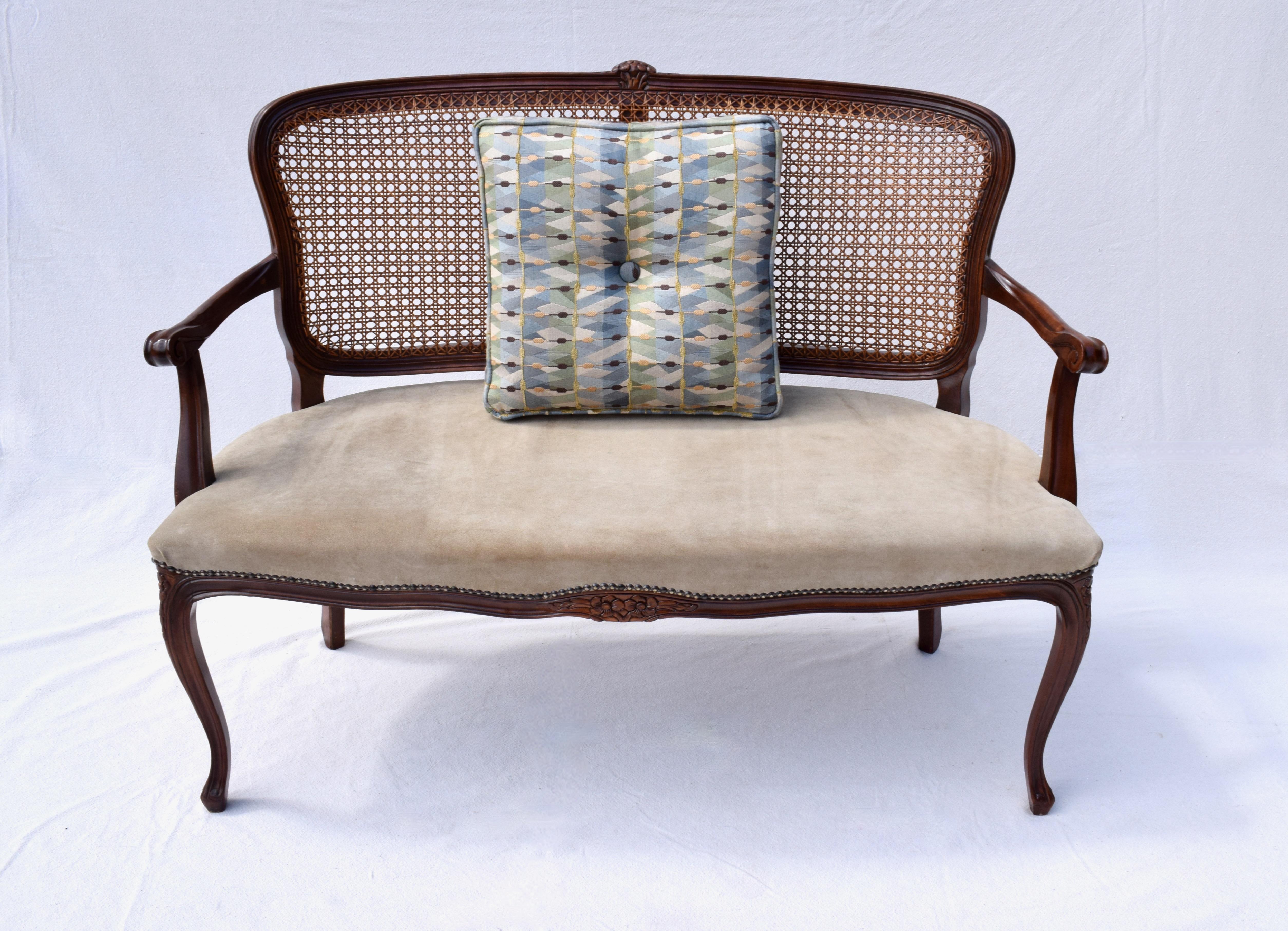 An exquisite Louis XV style French caned Mahogany settee or loveseat upholstered in soft suede with brass tack detailing. Circa 1980's made in Italy. Seat: 19