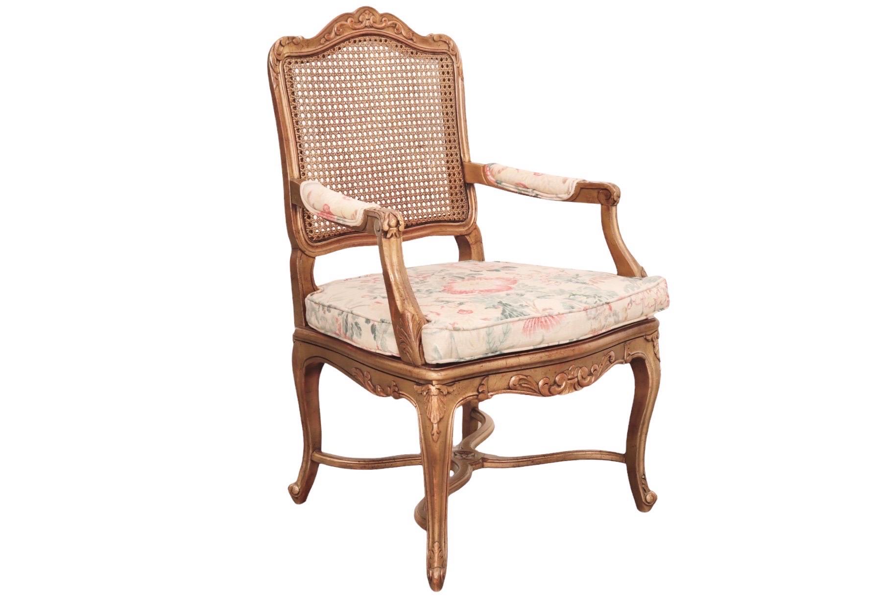 A Louis XV style carved fauteuil with a caned back and seat. The beechwood frame is carved in front and on the crest rail with a scrolled design. Cabriole legs supported with a curule stretcher finish in whorl feet. A loose box cushion and matching