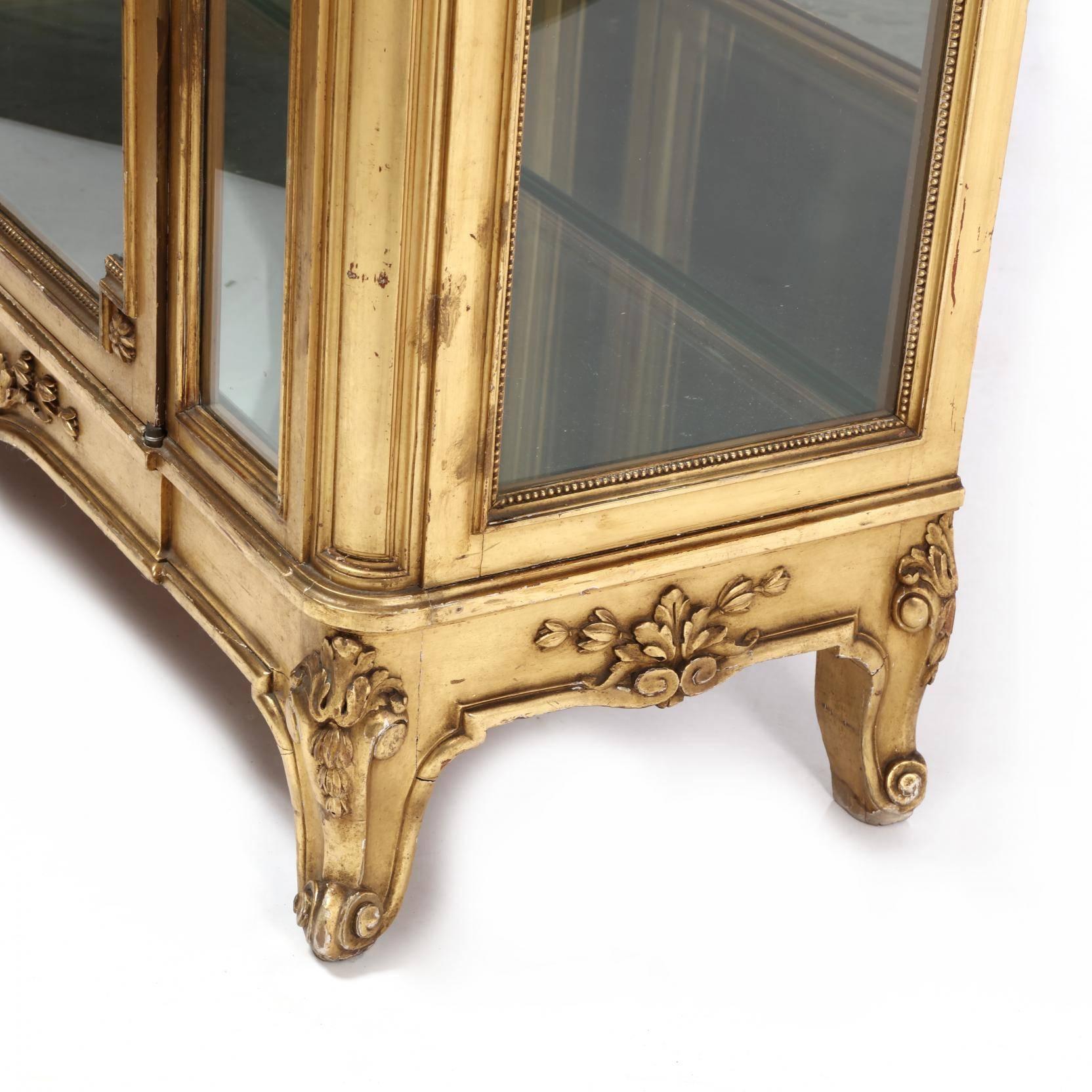 Early 20th century, one-piece form, rectangular flat wall case featuring an egg and dart cornice above a relief vine carved frieze, central hinged glass door opens to reveal a glass shelved interior with mirrored back, panelled quarter columns with