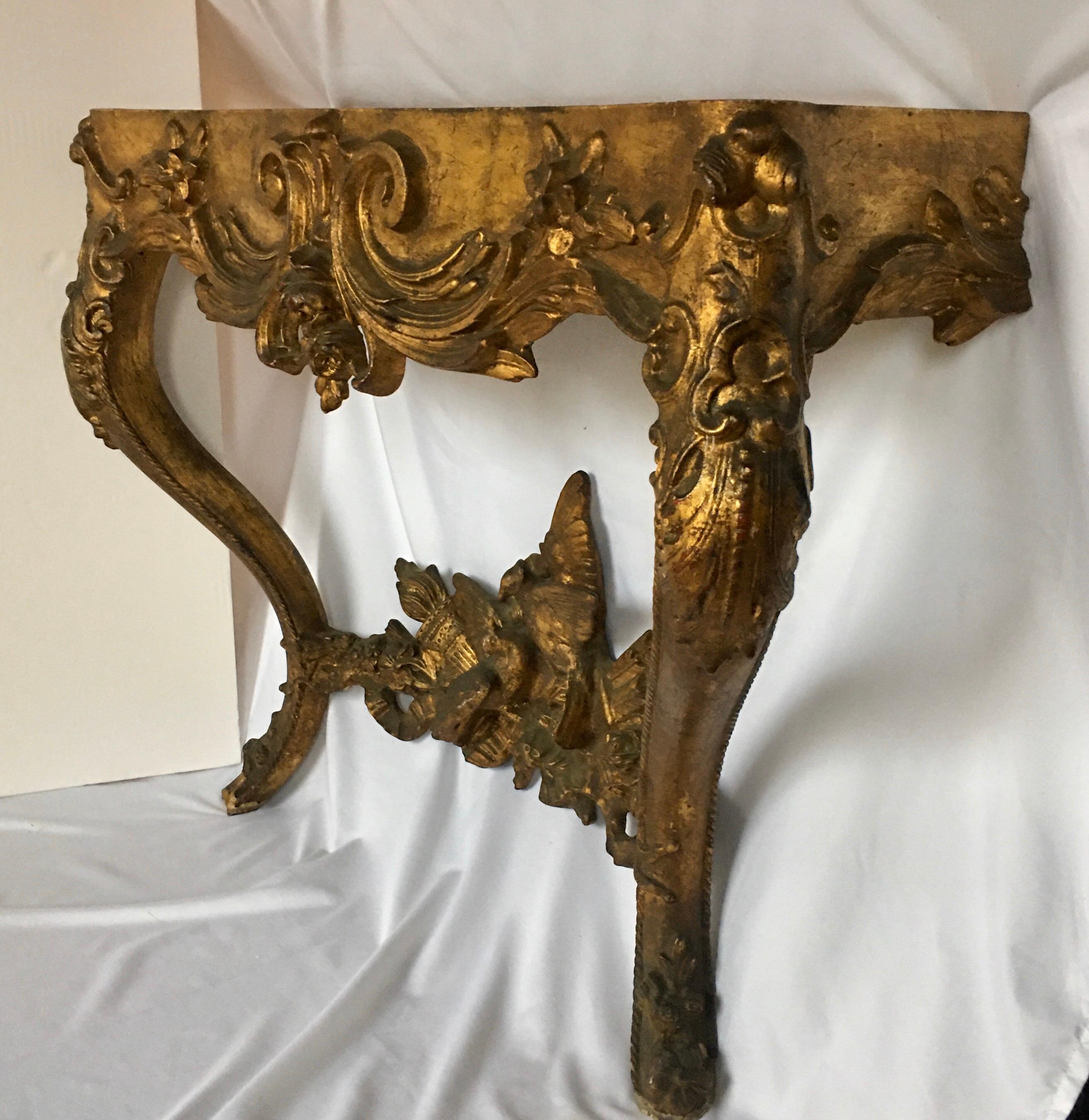 An elegant Louis XV French hand carved giltwood wall-mounted console table base. This highly detailed console features curved cabriole legs adorned with beautifully carved acanthus leaves and floral motifs. The dramatic curved legs are connected by