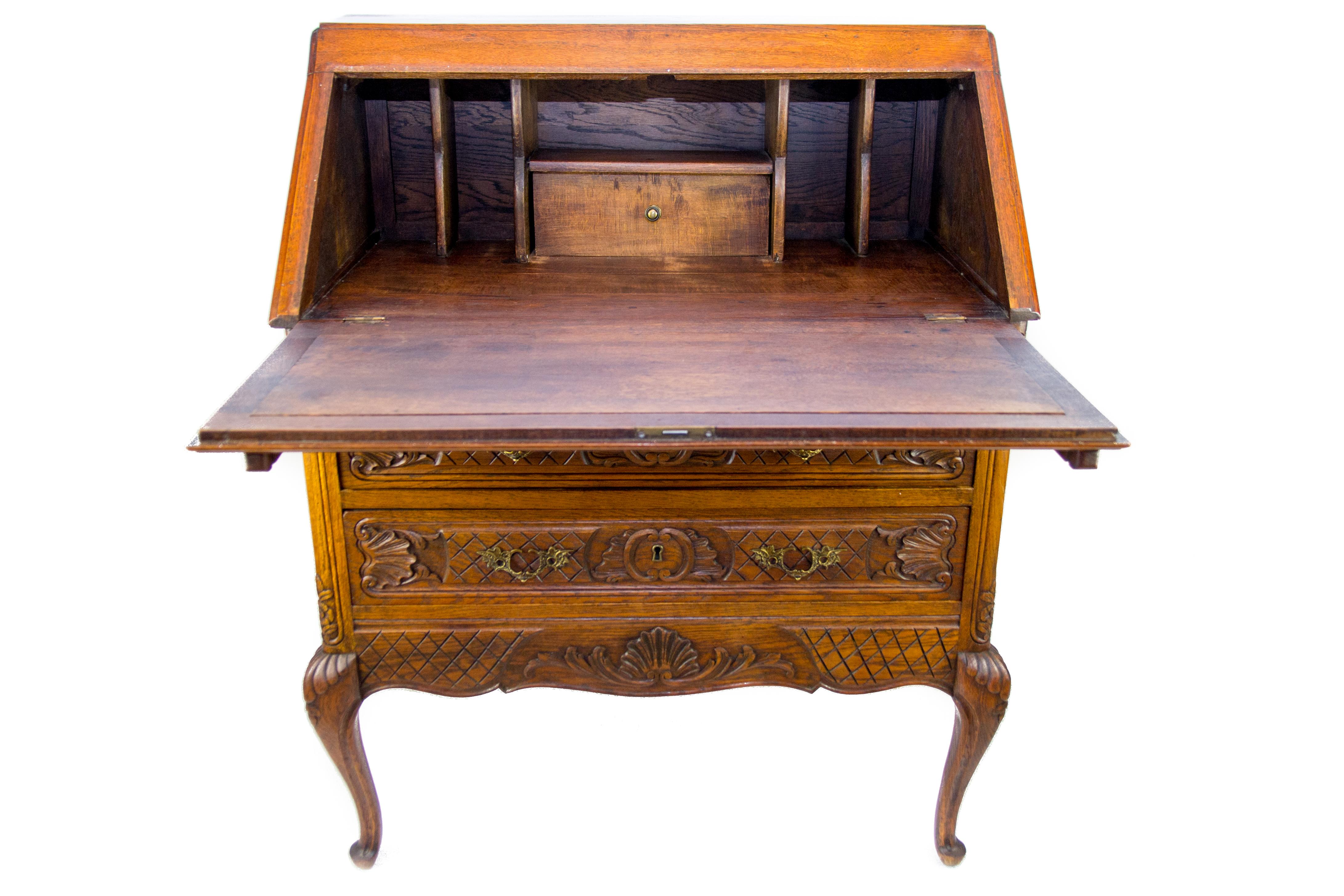 Louis XV Style carved oak drop front secretary or bureau or writing desk, two drawers with shaped bronze handles, made in France in the 1920s.
Opened it reveals a fitted desk interior with one drawer and a large writing area, held by two pullout /