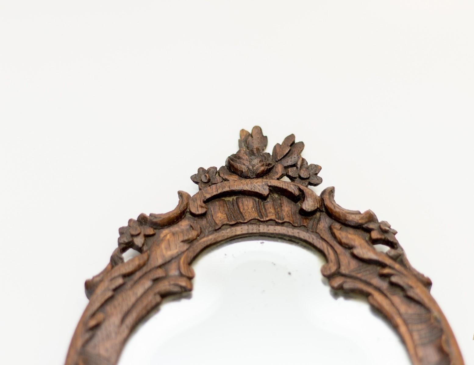 Ce miroir à main en bois de chêne sculpté dans le style Louis XV ou Rococo des années 1920, France, possède son miroir biseauté d'origine.
En bon état, conforme à l'âge et à l'utilisation. Quelques taches sombres sur le miroir antique - veuillez