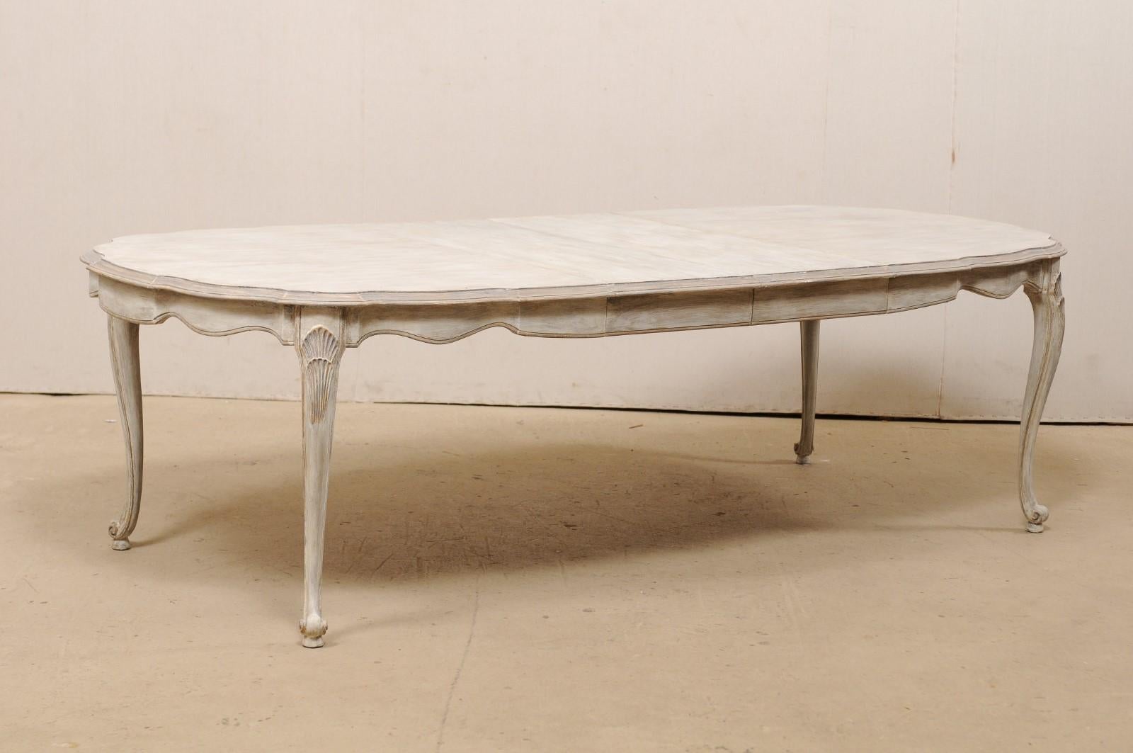 An American-made in Louis XV style dining room table with beautifully carved apron and legs from the mid-20th century. This vintage table, which was created in the French Louis XV style, features an oval-shaped top with a gracefully scalloped apron,