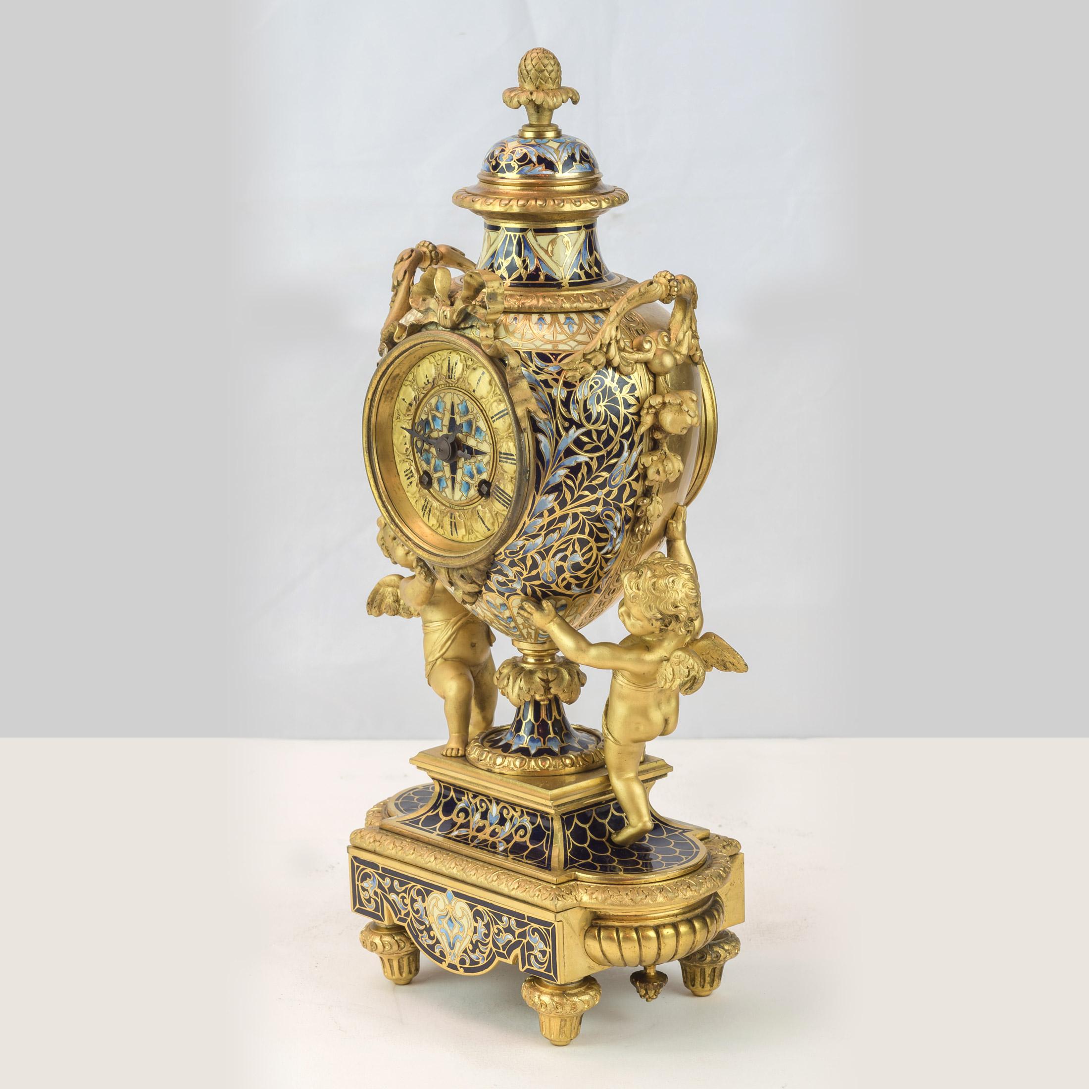 Louis XV style champleve enamel and gilt bronze clock
The urn form case housing a clock movement, surmounted by a flambeau trophy, the enamel dial with black enameled Roman numerals, adorned by twin winged cherubs, the movement marked 