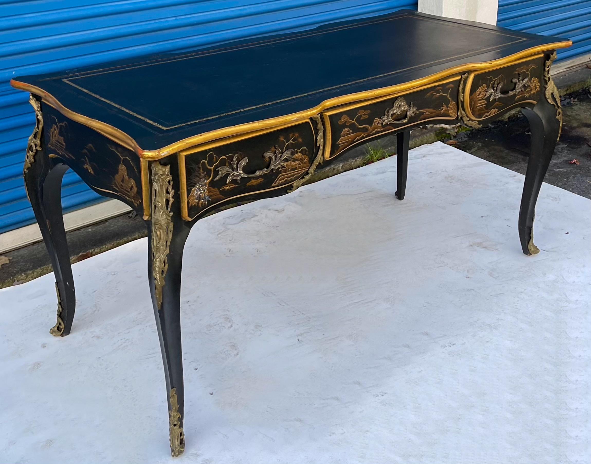 This is a wonderful piece! It is a French Louis XV style chinoiserie and gilt bronze bureau plat with black leather top. It has partner’s styling, but the drawers are functional on only one side. It is exceptional in it’s detail. It is in very nice