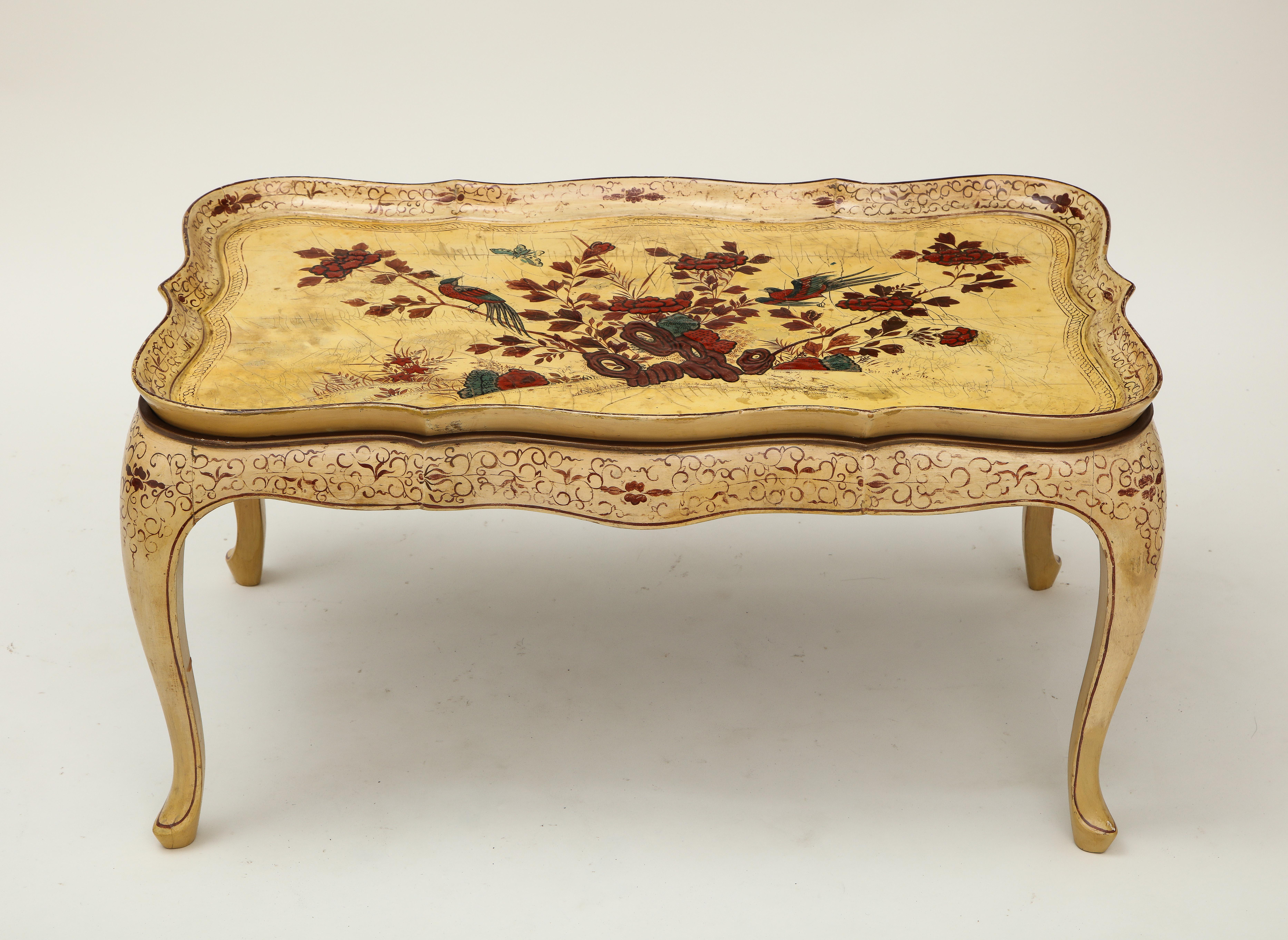 Decorated with floral blossoms and birds in crimson, blue, and gilt on an ivory ground; the shaped removable tray top on a conforming base with cabriole legs ending in pad feet.