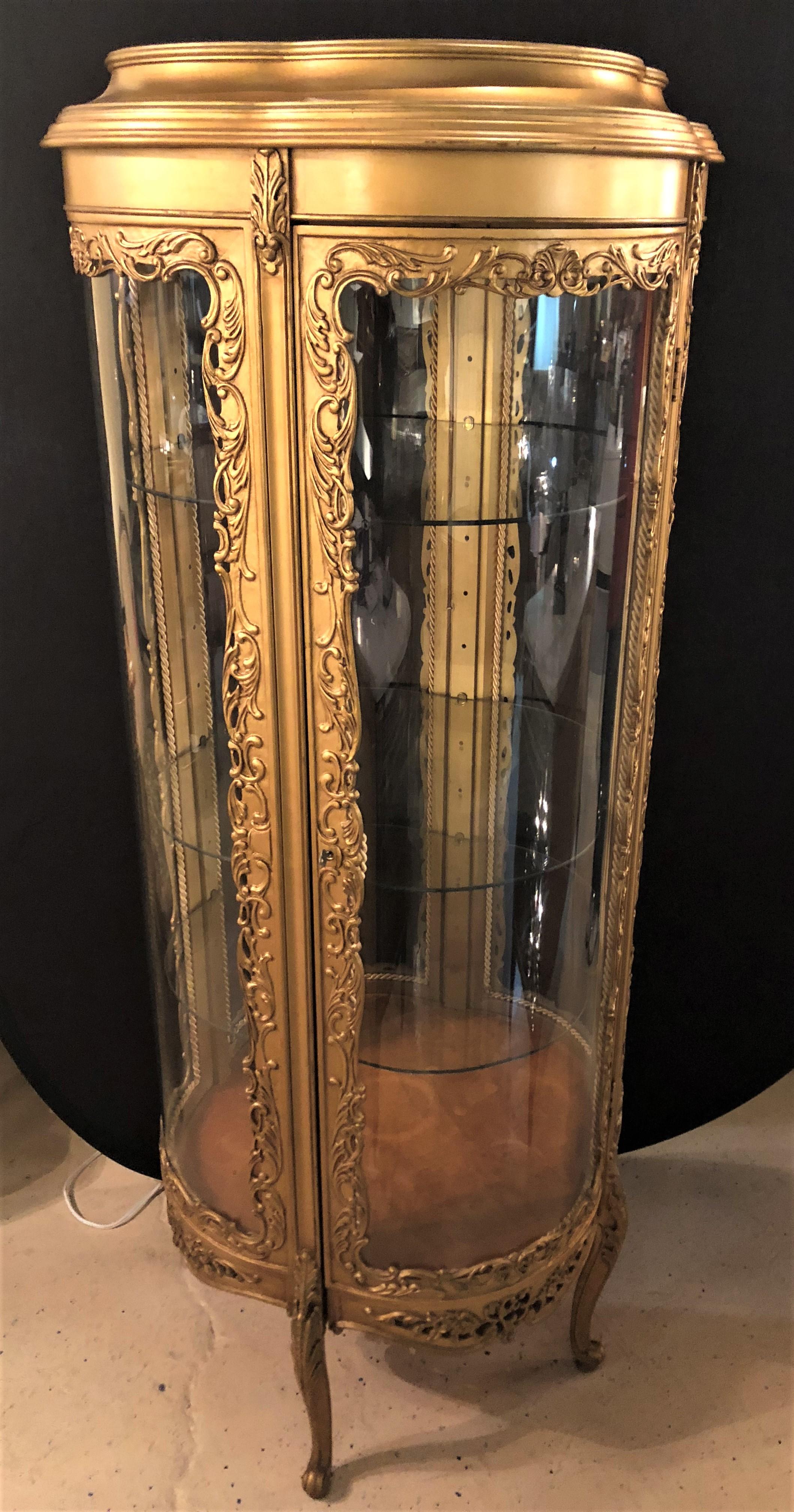 A wonderful Louis XV style clover circular giltwood lighted curio vitrine showcase. This simply stunning curio has a lighted interior along with three adjustable shelves in a round serpentine shape. The double clover like shape make this finely gilt