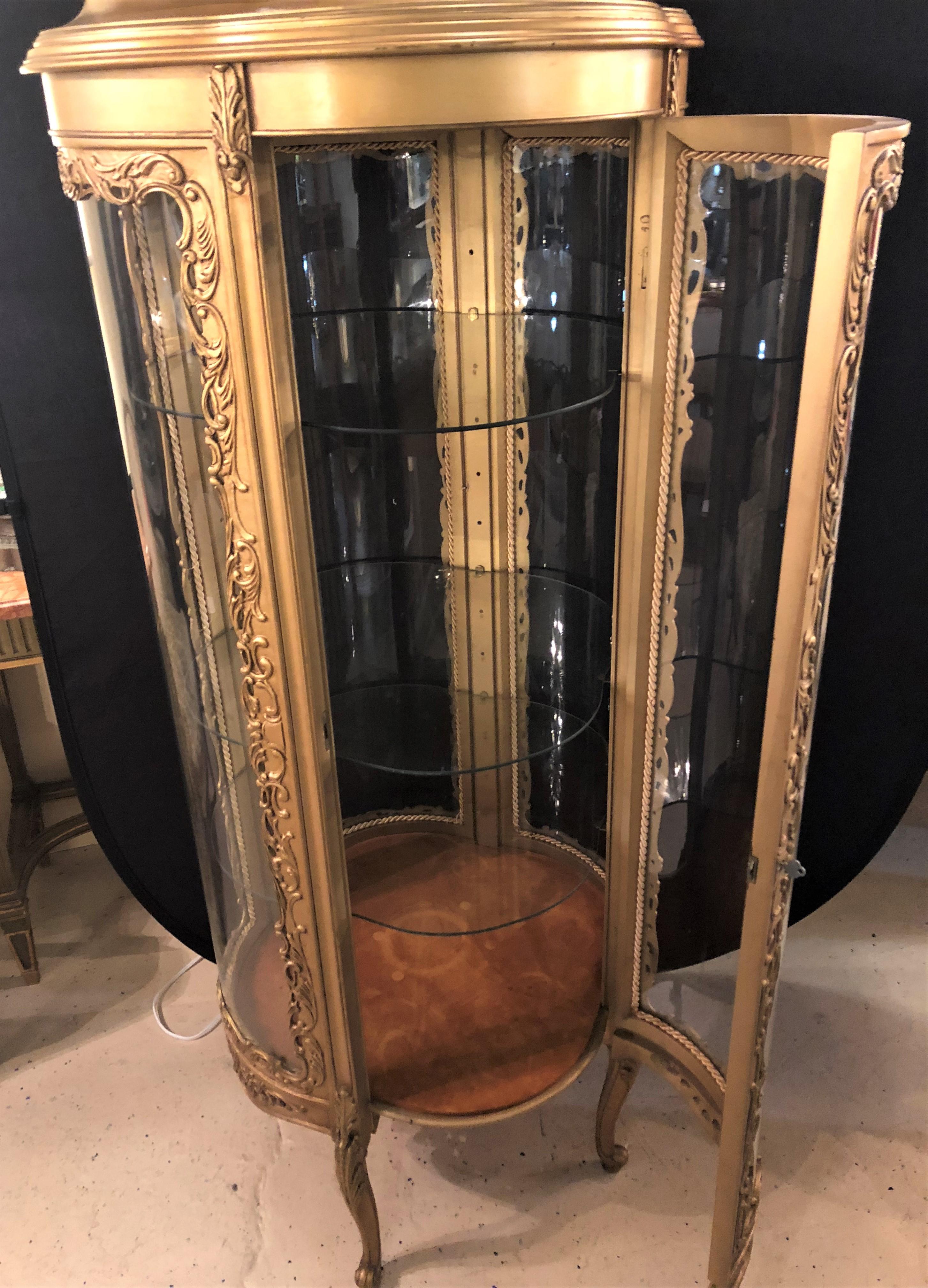 A wonderful Louis XV style clover circular giltwood lighted curio vitrine showcase. This simply stunning curio has a lighted interior along with three adjustable shelves in a round serpentine shape. The double clover like shape make this finely gilt