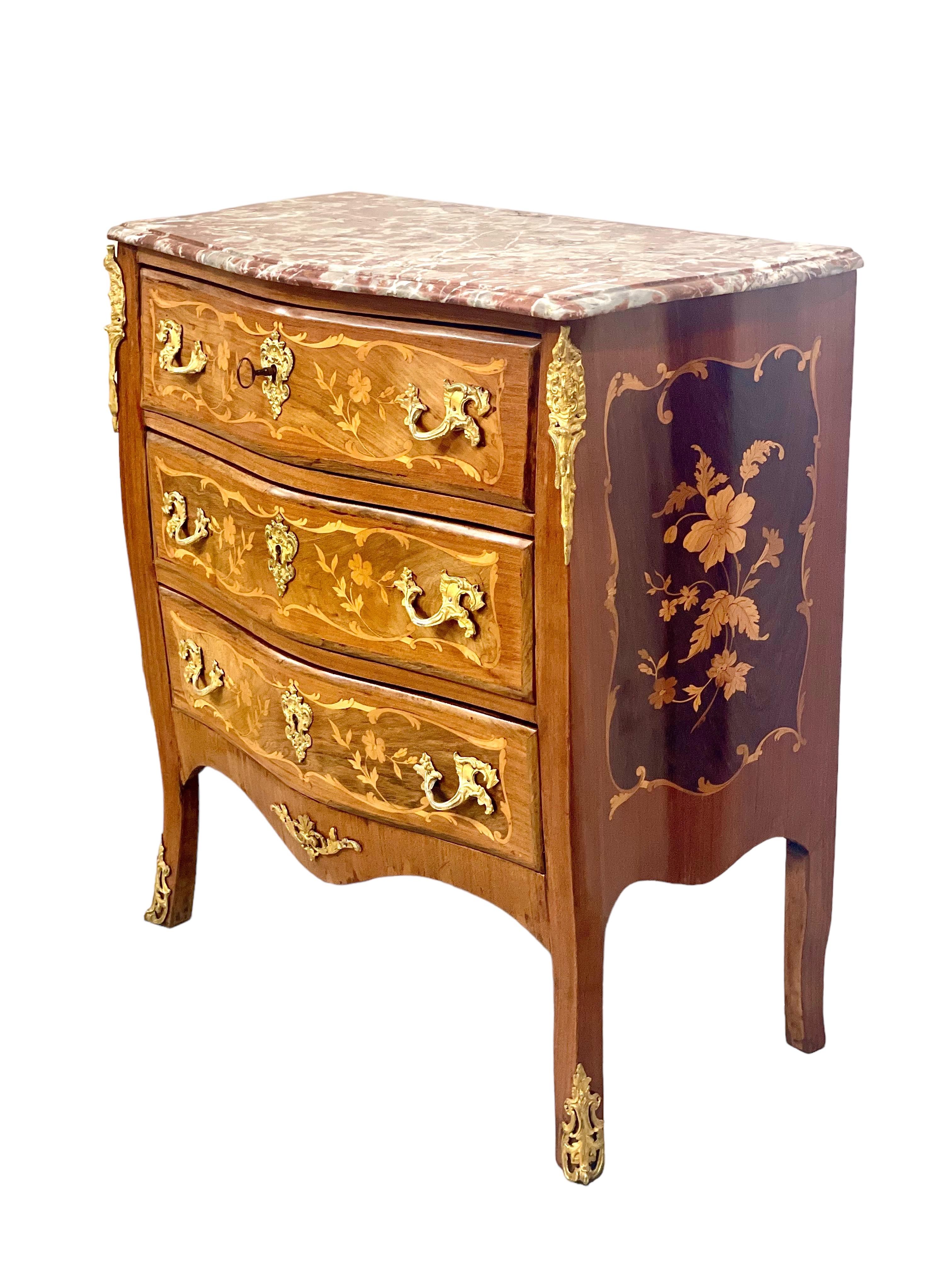 An exquisite and finely constructed Louis XV style chest of three drawers, with original pink- veined marble top and fabulous floral marquetry inlay to each drawer front and sides. Finished in luxurious Rococo style, this 19th century (Napoleon III