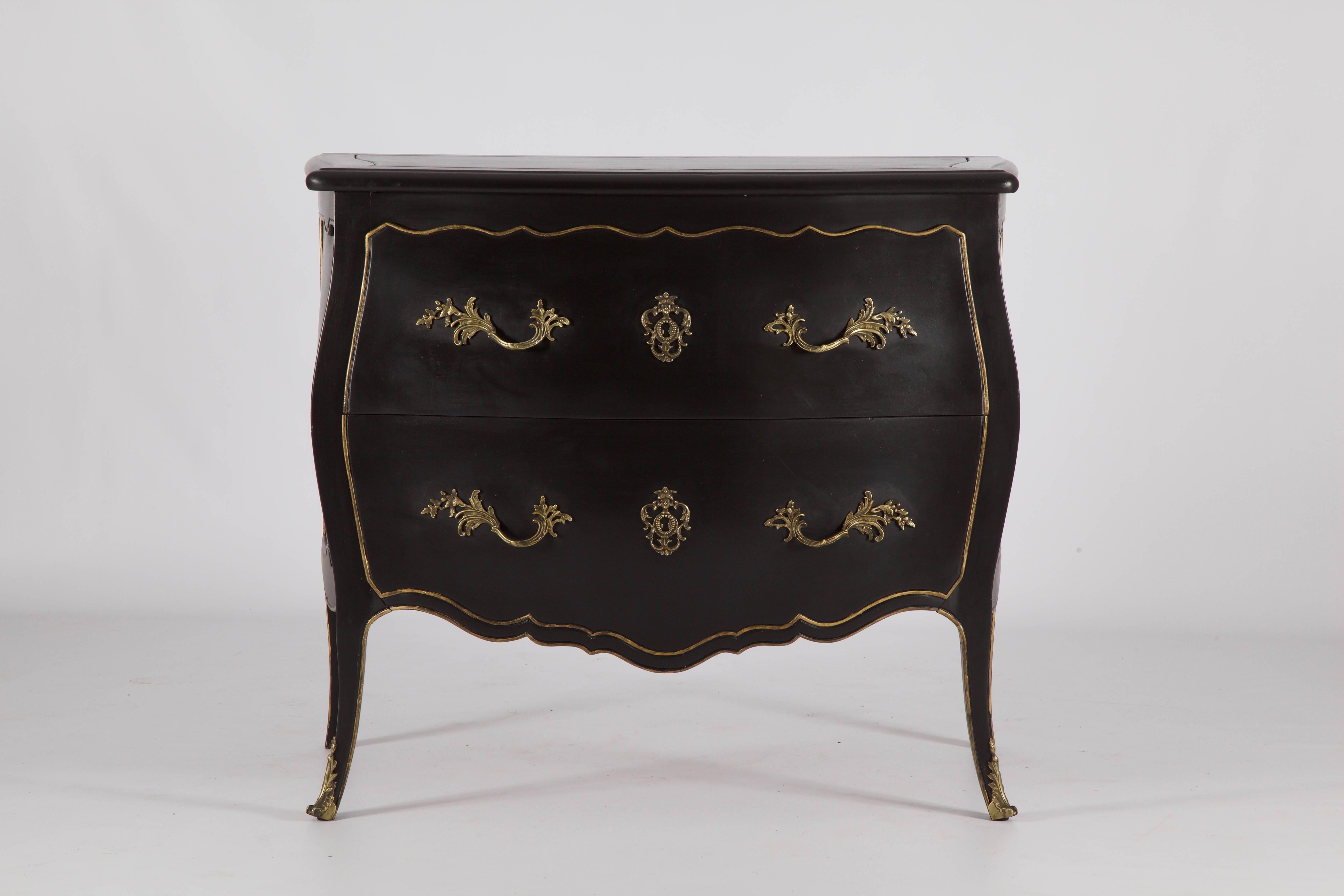 Louis XV style commode, hand-carved and hand finished in a black lacquer patina with gilded trim highlights. Completed with bronze ormolu drawer pulls and key holes in an aged patina.