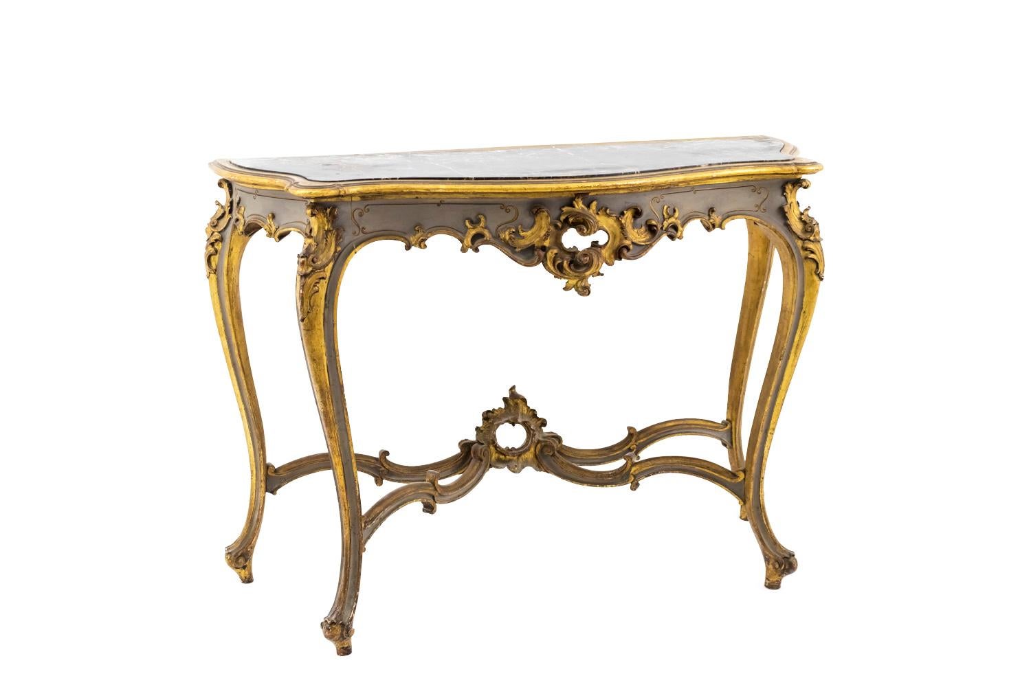 Louis XV style console in grey lacquered and giltwood standing on four cabriole legs finished by scrolls and linked each other by a curved stretcher composed by scrolls with an openwork rocaille central motif.
Scalloped apron with an acanthus