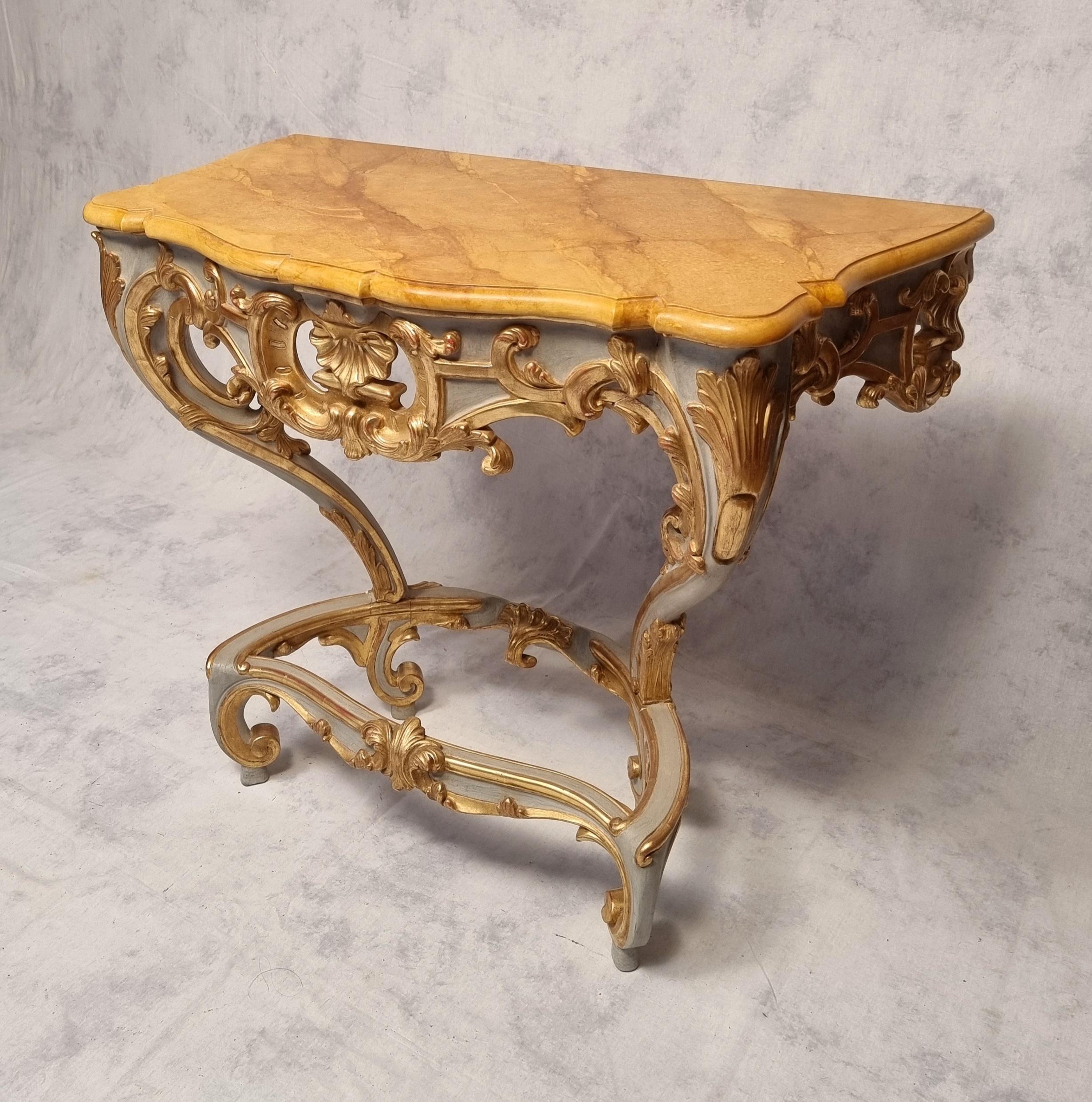 Louis XV style console on four legs. Original piece of furniture from the end of the 19th century in lacquered and gilded wood. This console has rich Rocaille ornaments. It does not require fixing to the wall, it rests on four feet. It is topped