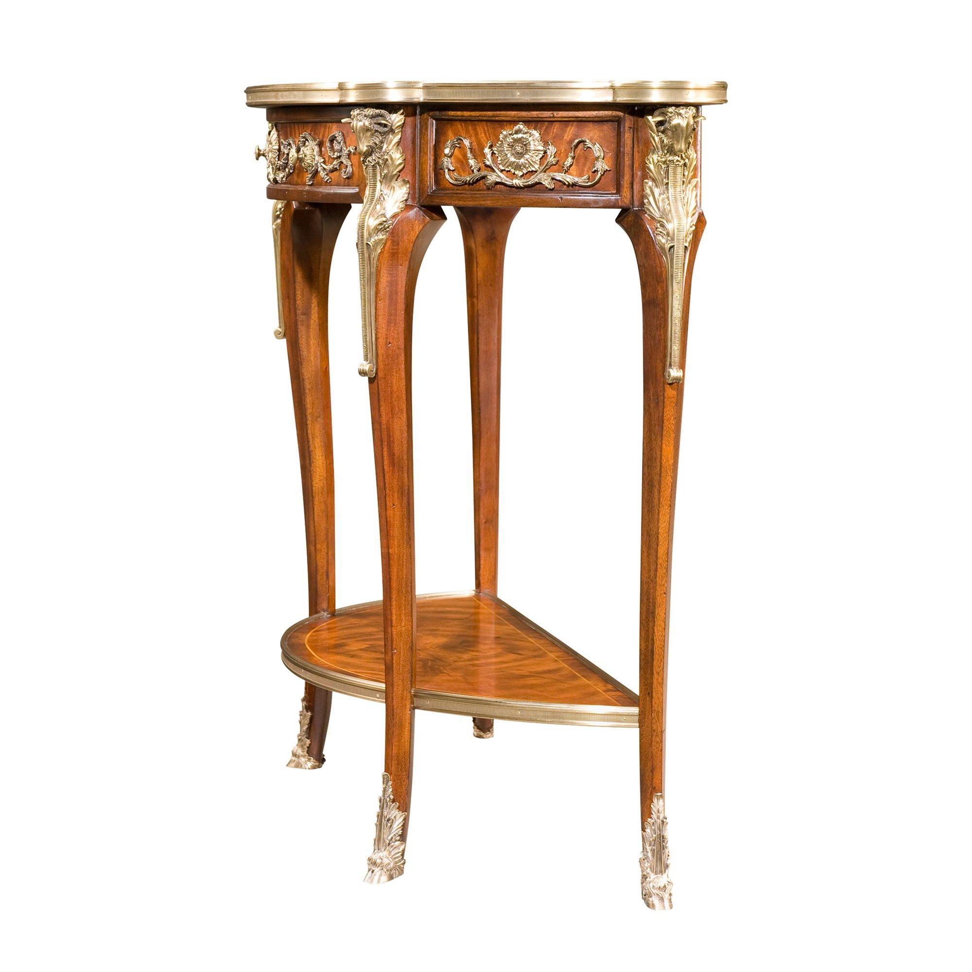 A mahogany and rosewood banded console table applied with very fine brass mounts, the brass bound top with a frieze drawer, on ram's head capital cabriole legs with hoof feet joined by an undertier.