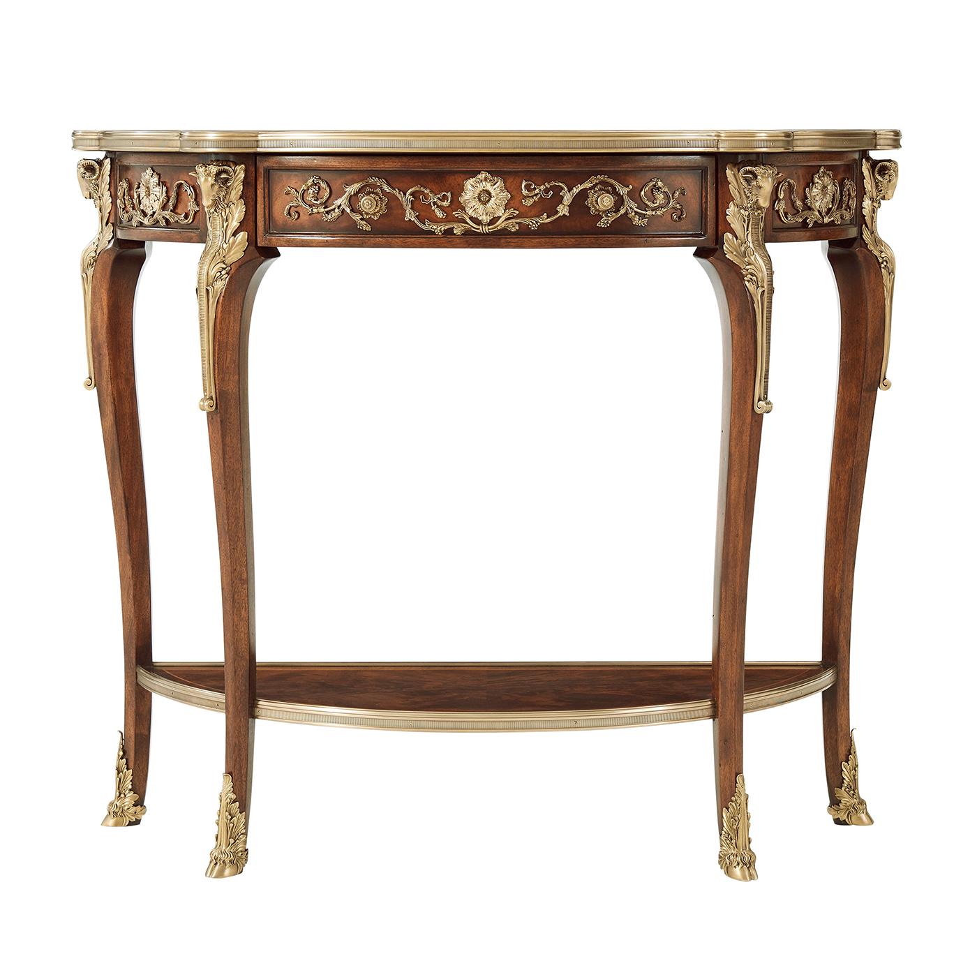 A Louis XV style mahogany and rosewood banded console table applied with very fine brass mounts, the brass bound top with a frieze drawer, on ram's head capital cabriole legs with hoof feet joined by an under tier. 

Dimensions: 40.25