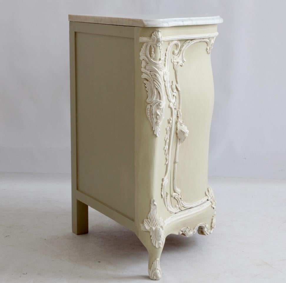 A Louis XV style corner cabinet hand carved in solid wood and hand painted.
Fine carving all around with flowers and foliage executed in the style of master cabinet makers from the late 1700s.
There is a 30mm Carrara honed marble with an ogee edge