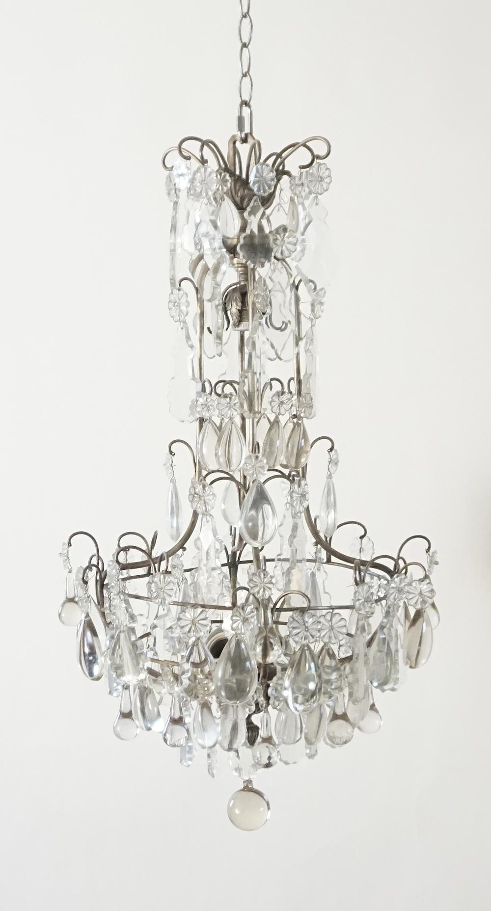 French, circa 1930 Louis XV style chandelier having silver-gilt metal frame with internal sockets hung with various shapes and sizes of faceted and smooth cut crystal prisms.

Additional search terms:  Bagues, Jansen