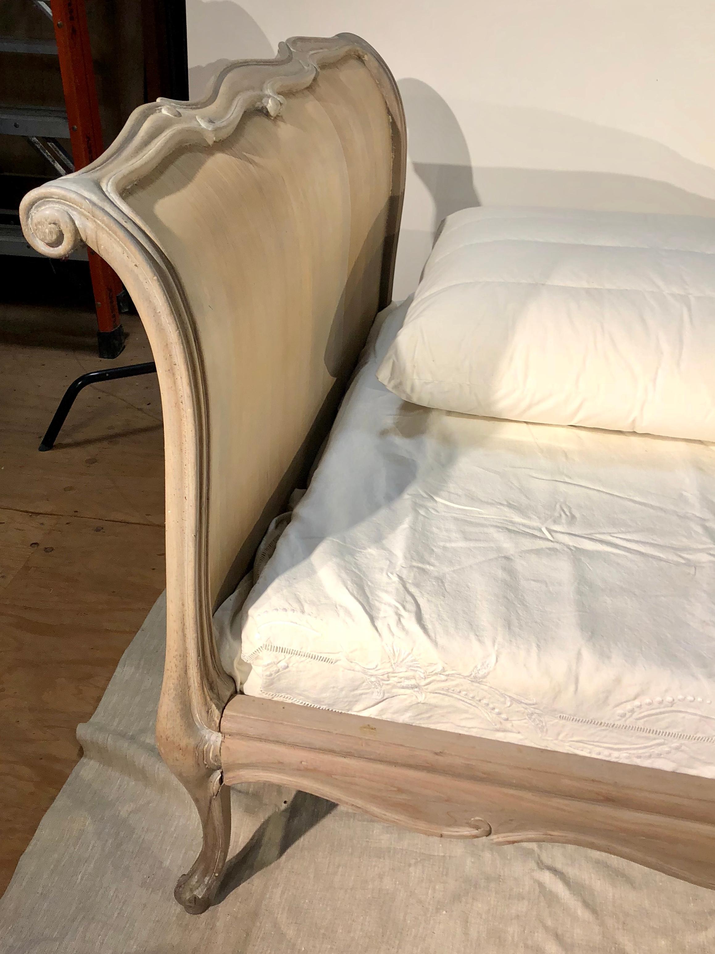 A Louis XV style day bed with curved head and foot boards and scalloped siderails, circa 1940, French, with a new standard twin size box and mattress (wrapped in original packaging). The bed can be used away from the wall as both sides are finished.