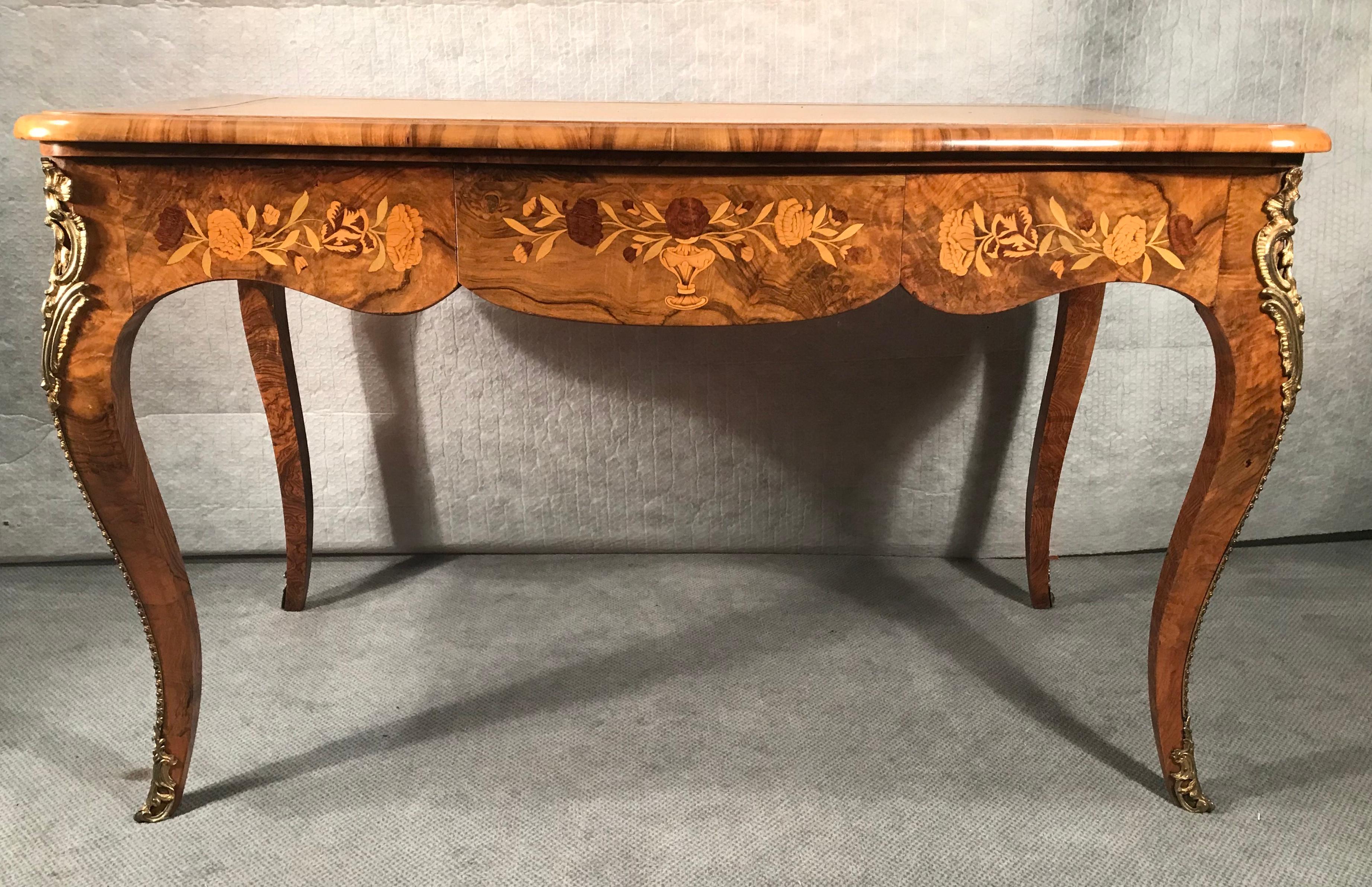 Louis XV style desk, France circa 1890, walnut veneer with flower marquetry in elm and maple. The top is partially covered with leather. It is designed to Stand against a wall. The table is in good original condition. It ships from Germany, shipping