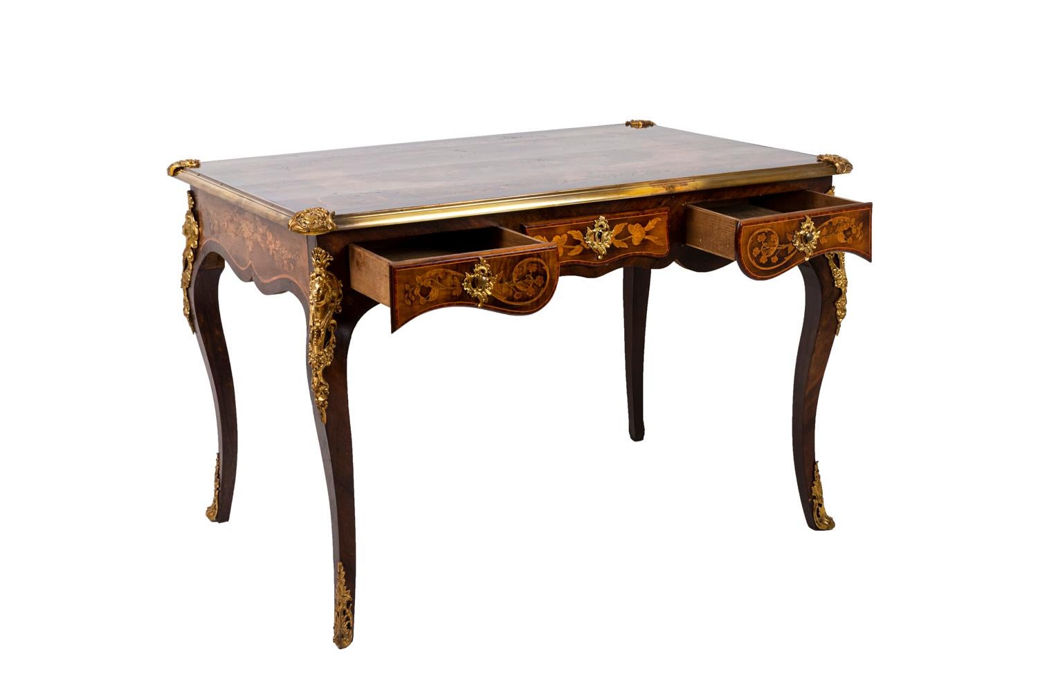 Louis XV style desk in kingwood standing on four cabriole legs and opening by three drawers. Decor of flowers and vegetal scrolls in inlaid exotic woods on the tray, the drawers fronts and the lateral studs. Chiseled and gilt bronze ornamentations