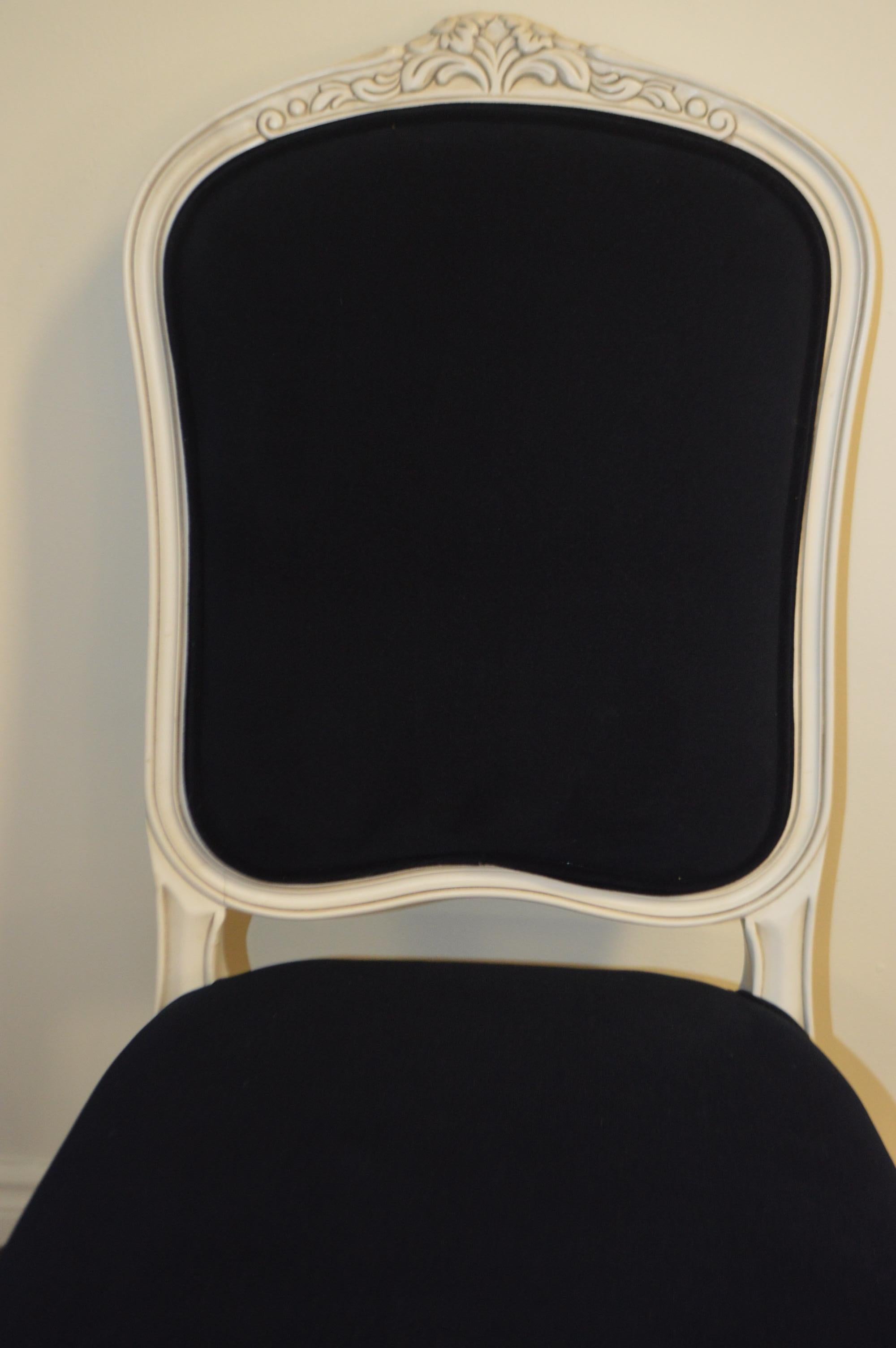 This dining chair is generous in size, it also has some charming carved elements at the top of the frame as well as the legs. It is showing here with a slightly distressed white paint finish and upholstered with a washable velvet in navy. This