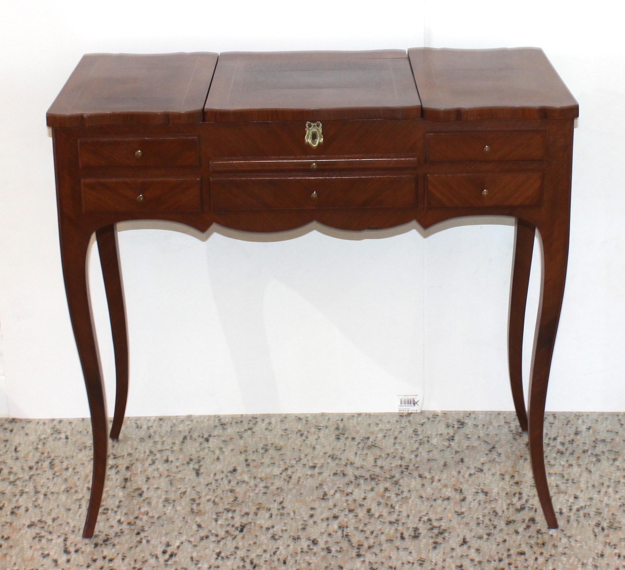 This stylish and chic dressing table is in the Louis XV style, and was fabricated sometime in the 1920s-1930s. The center opens up to reveal a dressing mirror, and just beneath that is a pull-out tray and single drawer. And to the left and right of