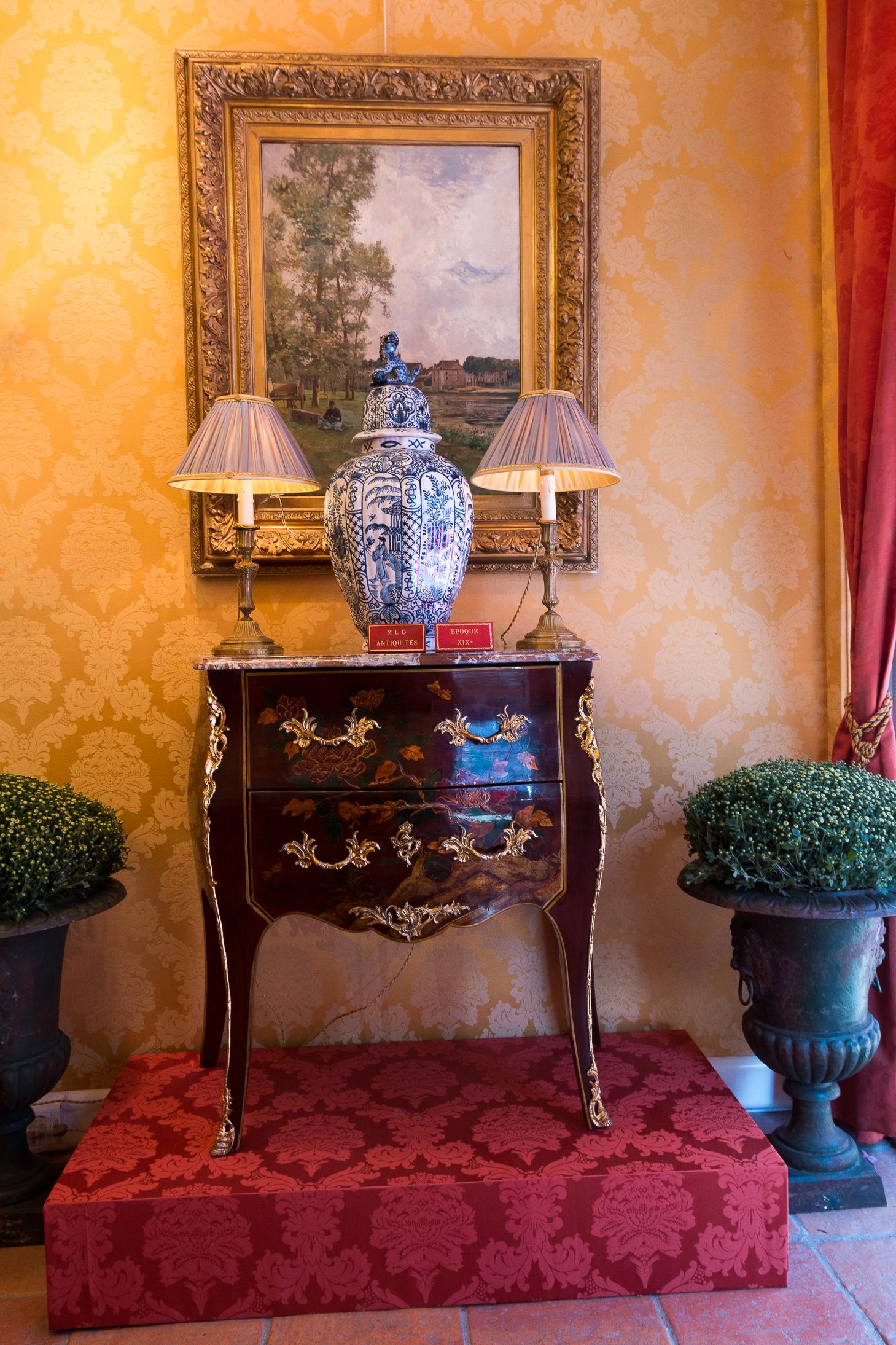 A French Louis XV style lacquer two-drawer commode from the early 20th century, with hand-painted gold and black chinoiserie scenes, ormolu mounts and Royal-Breche marble top. 

This French two-drawer commode features on the front and the two