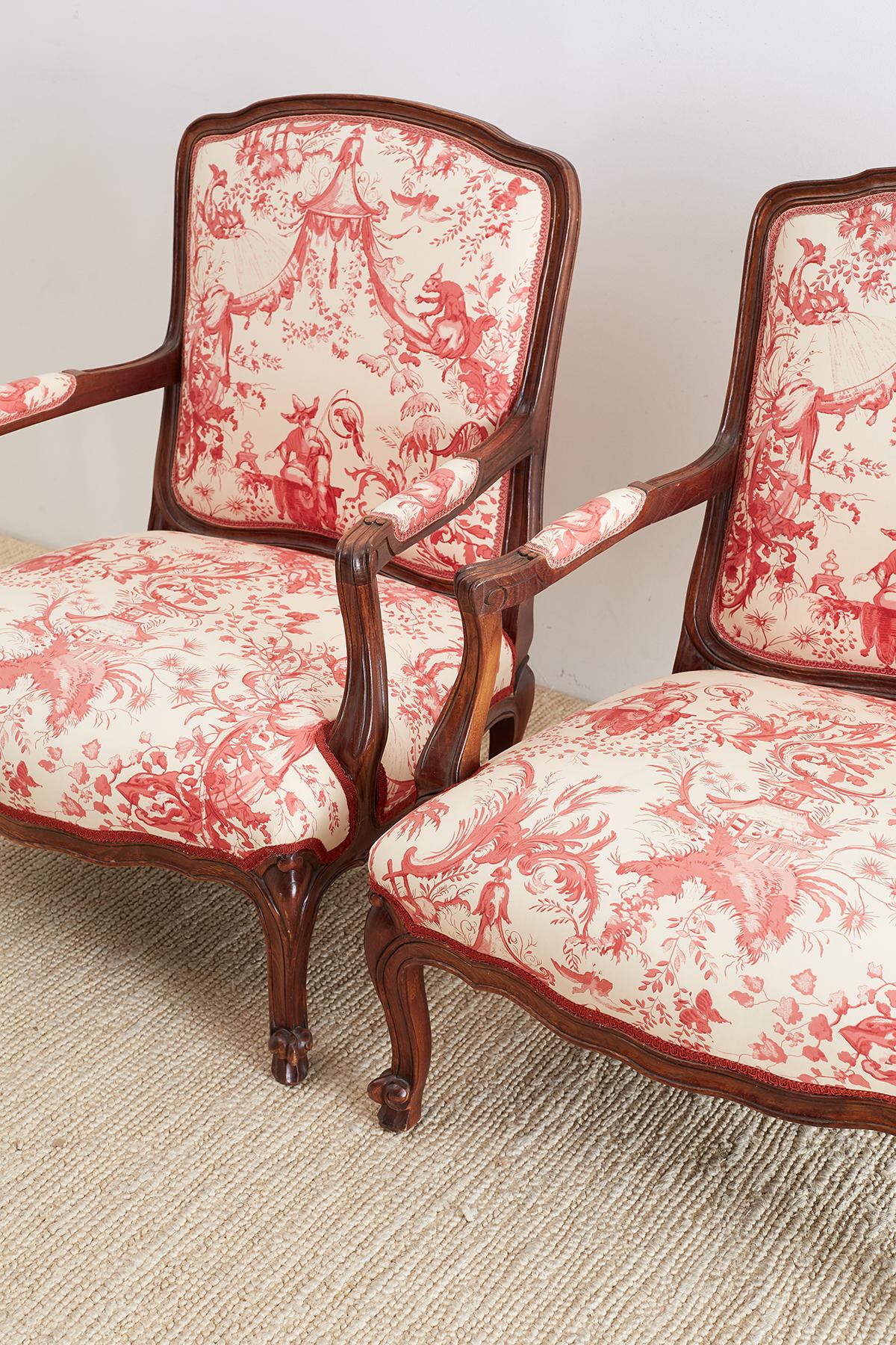 Stunning pair of French Louis XV style fauteuils or armchairs featuring Scalamandre petite chinoiserie fabric in red and cream. These 20th century armchairs were produced in Hickory, North Carolina and were made on a large-scale with generous