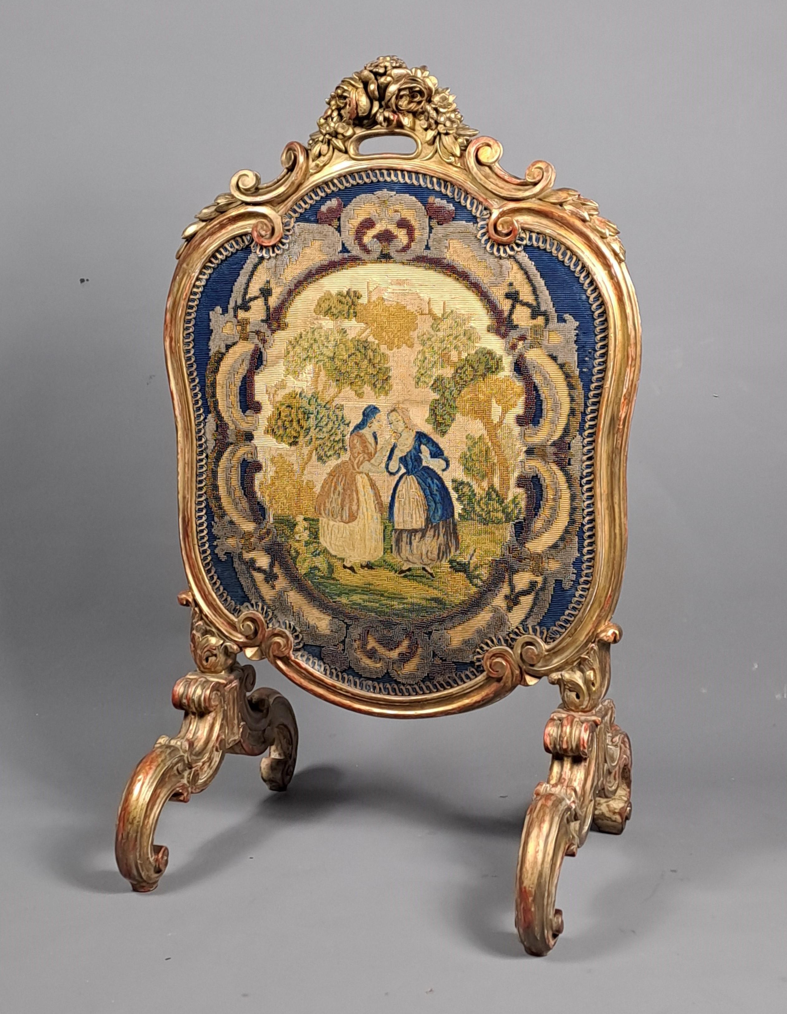 Richly carved gilt wood fire screen in the Louis XV rocaille style featuring a superb polychrome tapestry enhanced with pearls decorated with an animated scene (confidences of a 