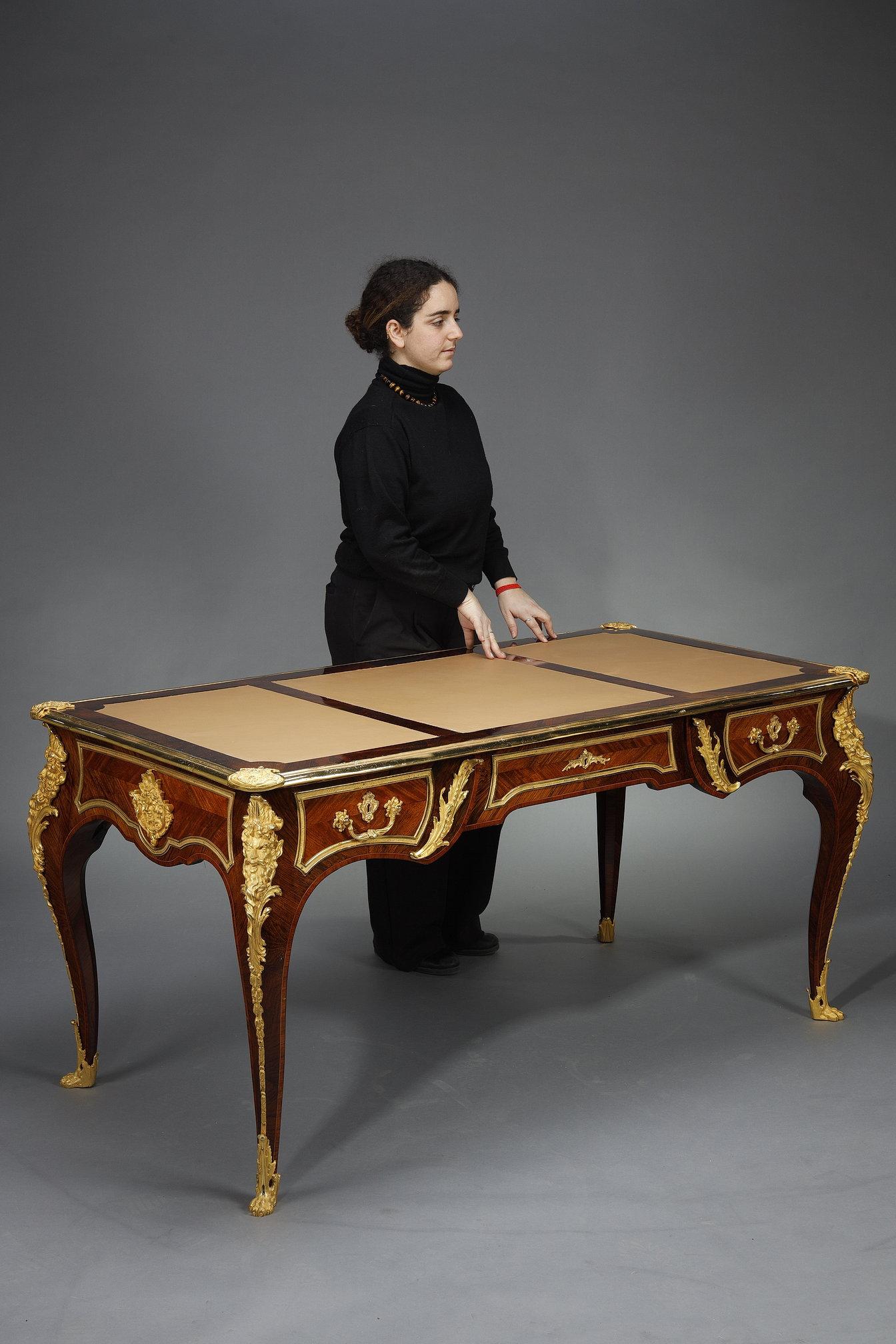 Scrivania piatta con intarsi in palissandro e ricchi ornamenti in ormolu, decorata con teste di satiro e fogliame. Bellissimo lavoro in stile Luigi XV, simile a quello prodotto da Linke, Beurdeley o Dasson. Top in pelle a tre scomparti.
