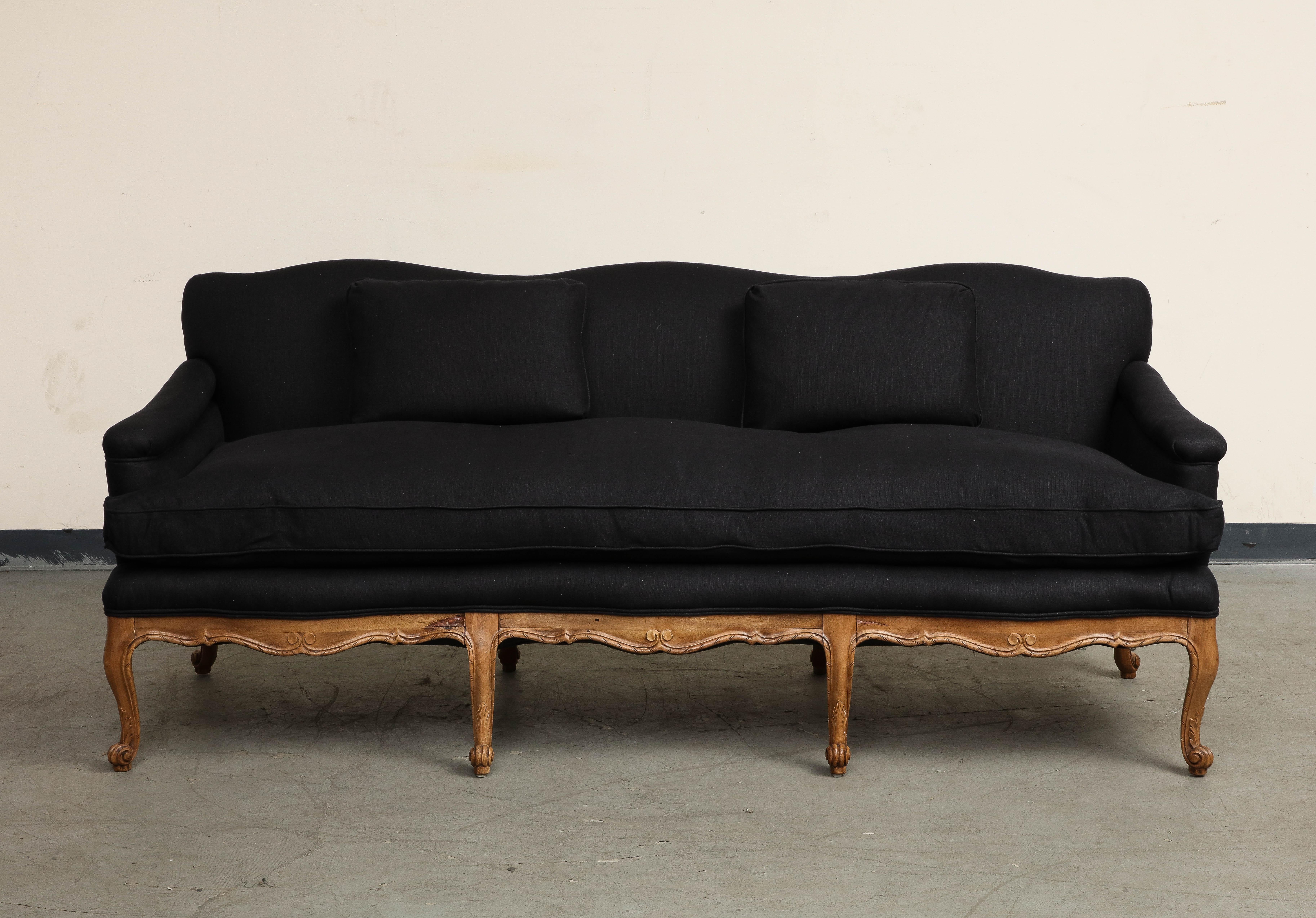 Louis XV Style French Carved Walnut Sofa, c. 1920s, newly reupholstered in heavyweight black linen. Frame and elegant scroll legs have been restored and refinished to natural walnut. 
