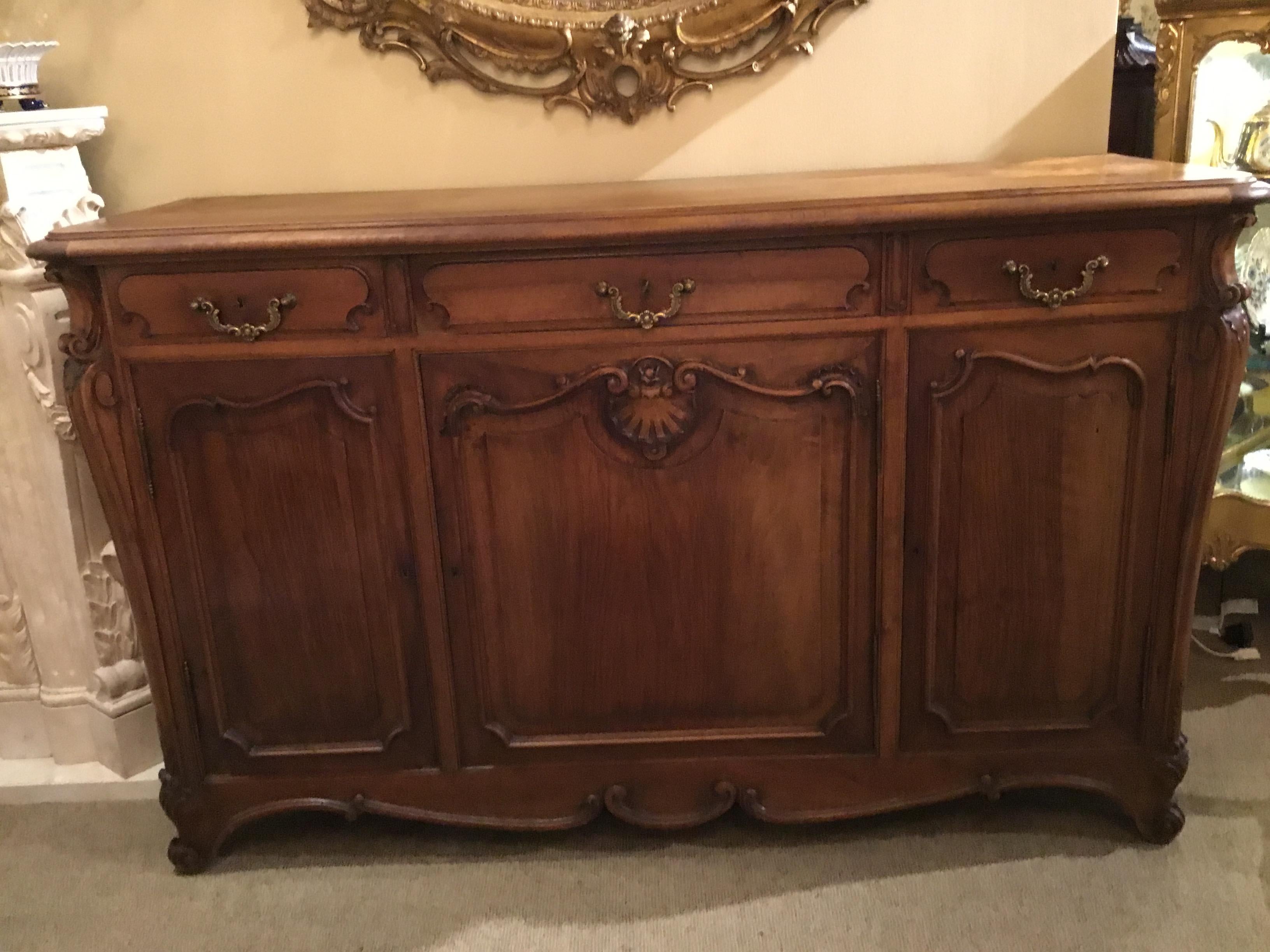 French Louis XV-style carved walnut sideboard, Barbie (Armand Barbie) ebaniste
Bordeaux, late 19th century, rounded rectangular top, over three frieze drawers, having
scrolled gilt metal hanging pulls, carved scallops and scroll work to three