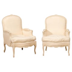 Louis XV Style French Cream Painted Wood Carved Bergères Chairs, a Pair
