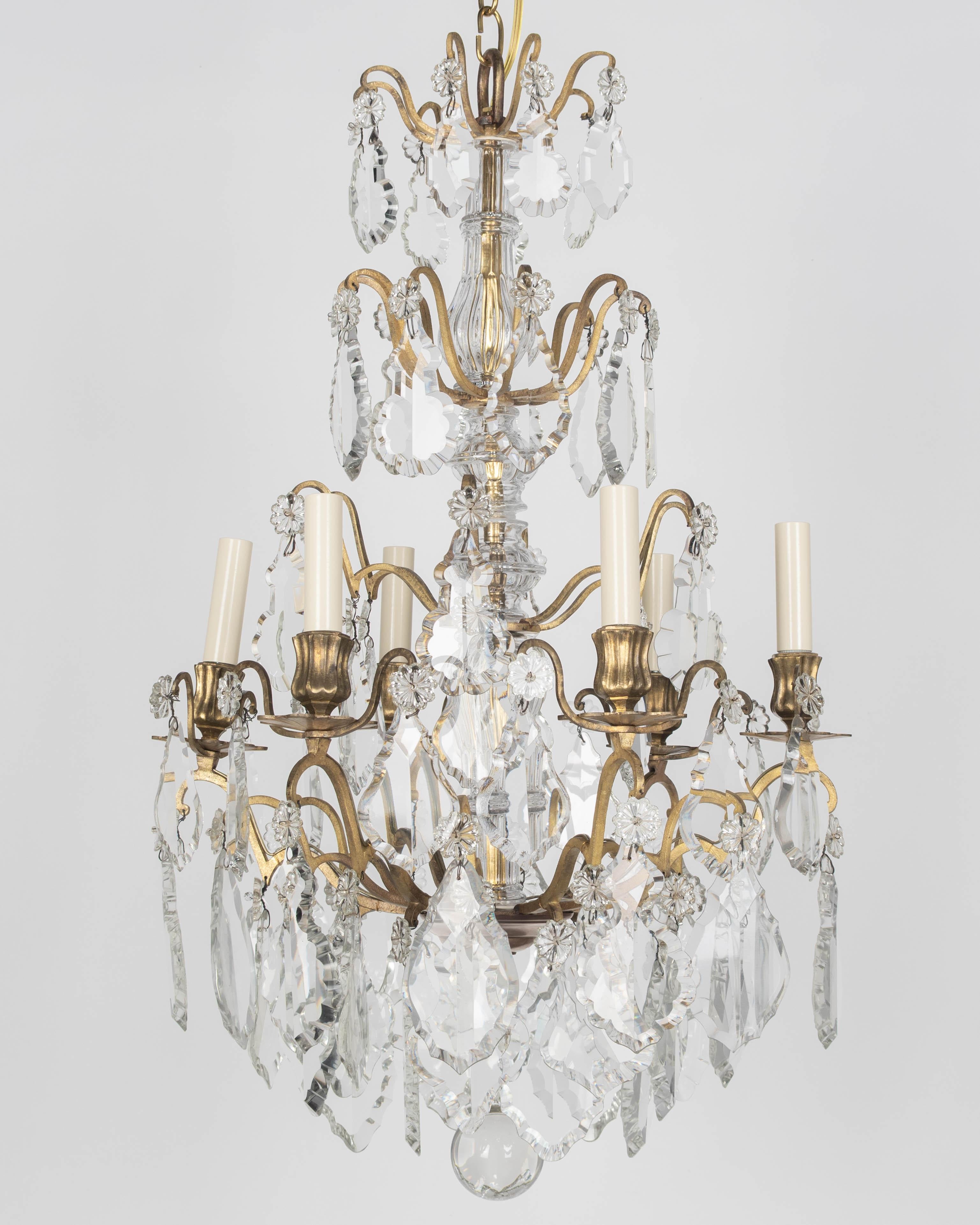 Lustre à six lumières de style Louis XV français du début du XXe siècle, composé d'un assortiment de prismes et de pendentifs en cristal avec rosettes, colonnes centrales nervurées et boule de cristal. Tout le cristal est d'origine et intact,