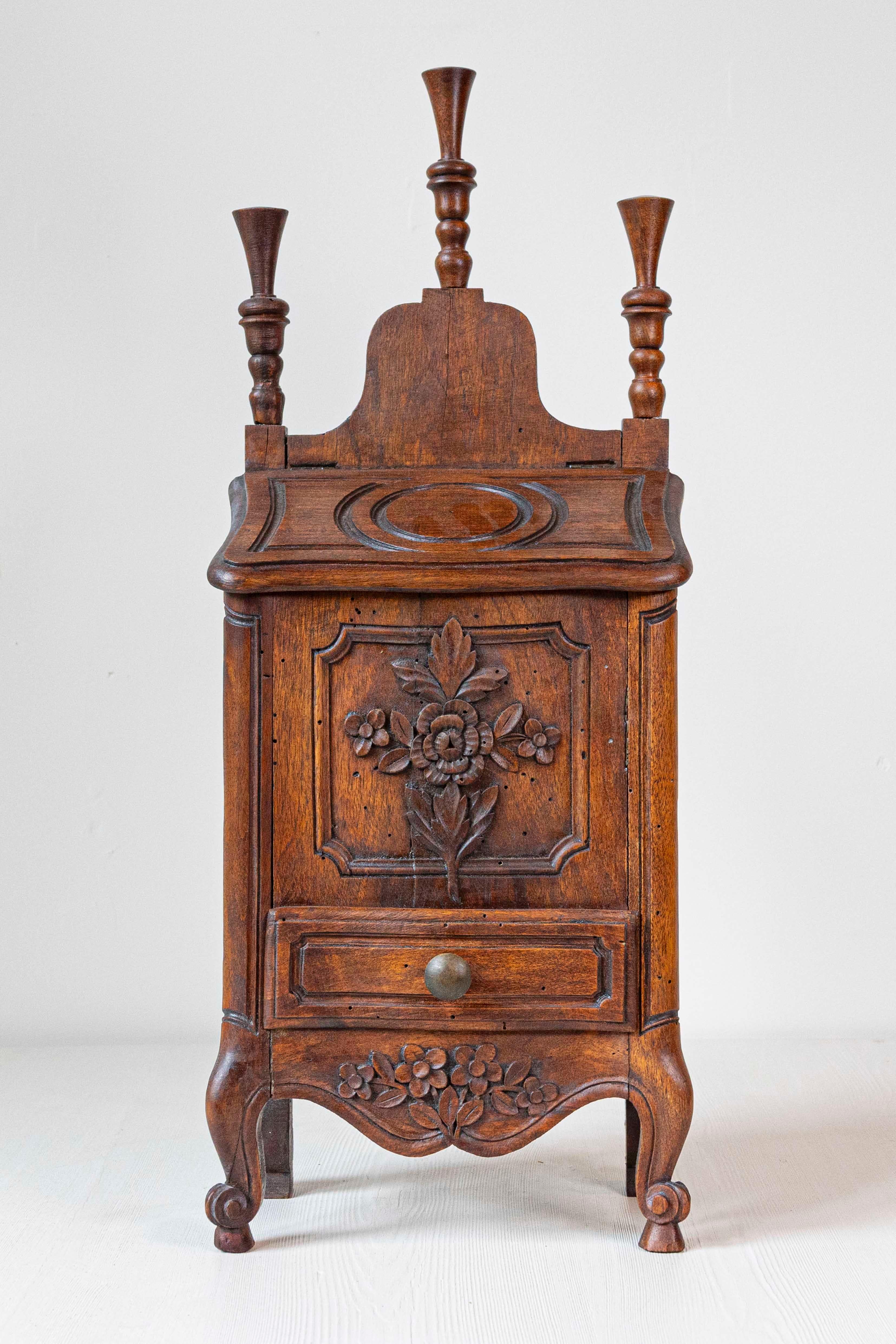 This 19th-century French Louis XV-style walnut farinerio flour box exemplifies the perfect union of form and function. Crafted from warm-toned walnut, the box features intricately carved floral motifs on its front panel and apron, reflecting the
