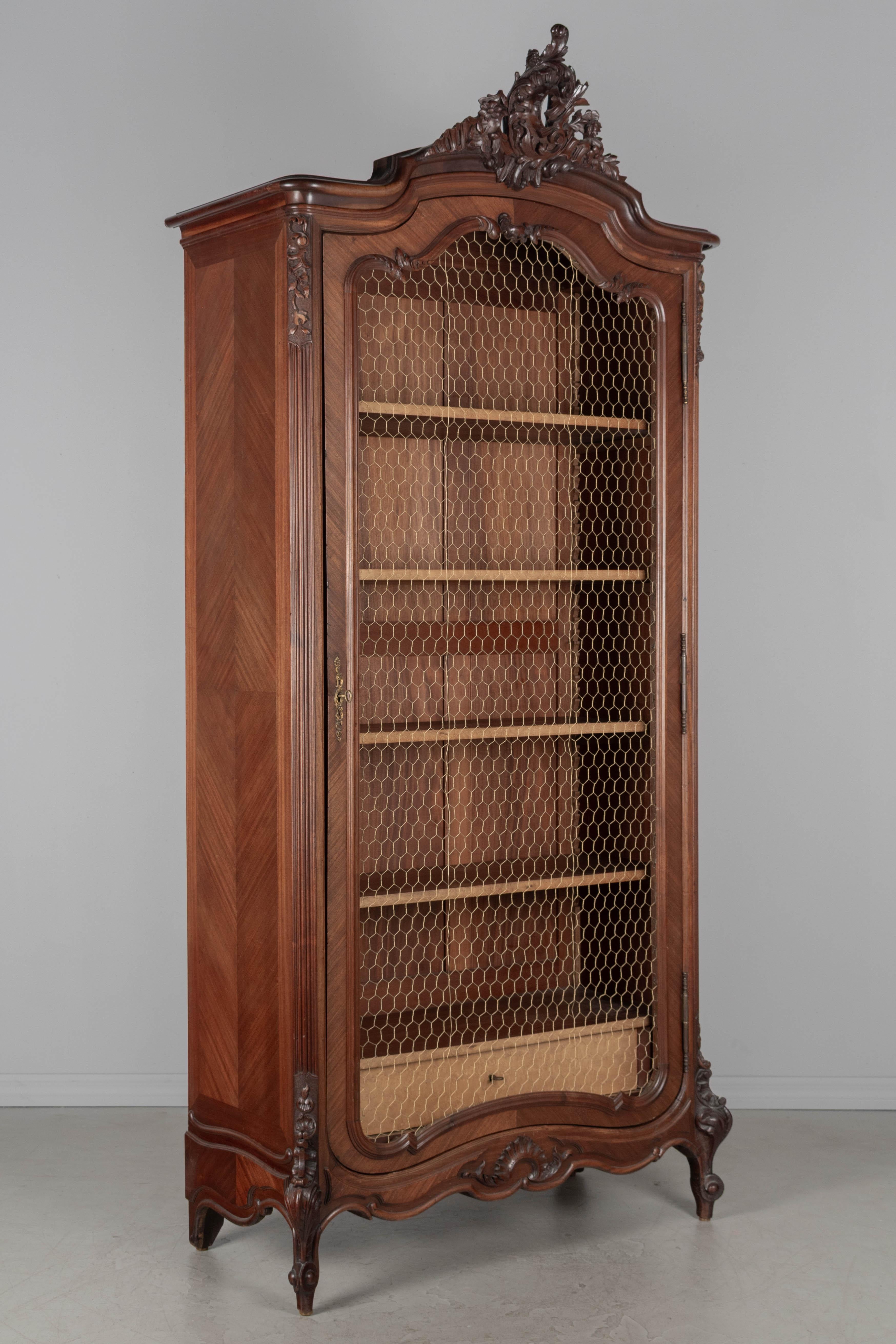 Armoire in mogano in stile Luigi XV dei primi del Novecento con corona intagliata e dettagli angolari. La porta, un tempo a specchio, ha una nuova griglia in filo d'acciaio verniciato in oro. Il pannello di supporto in legno rimane e sarà incluso.