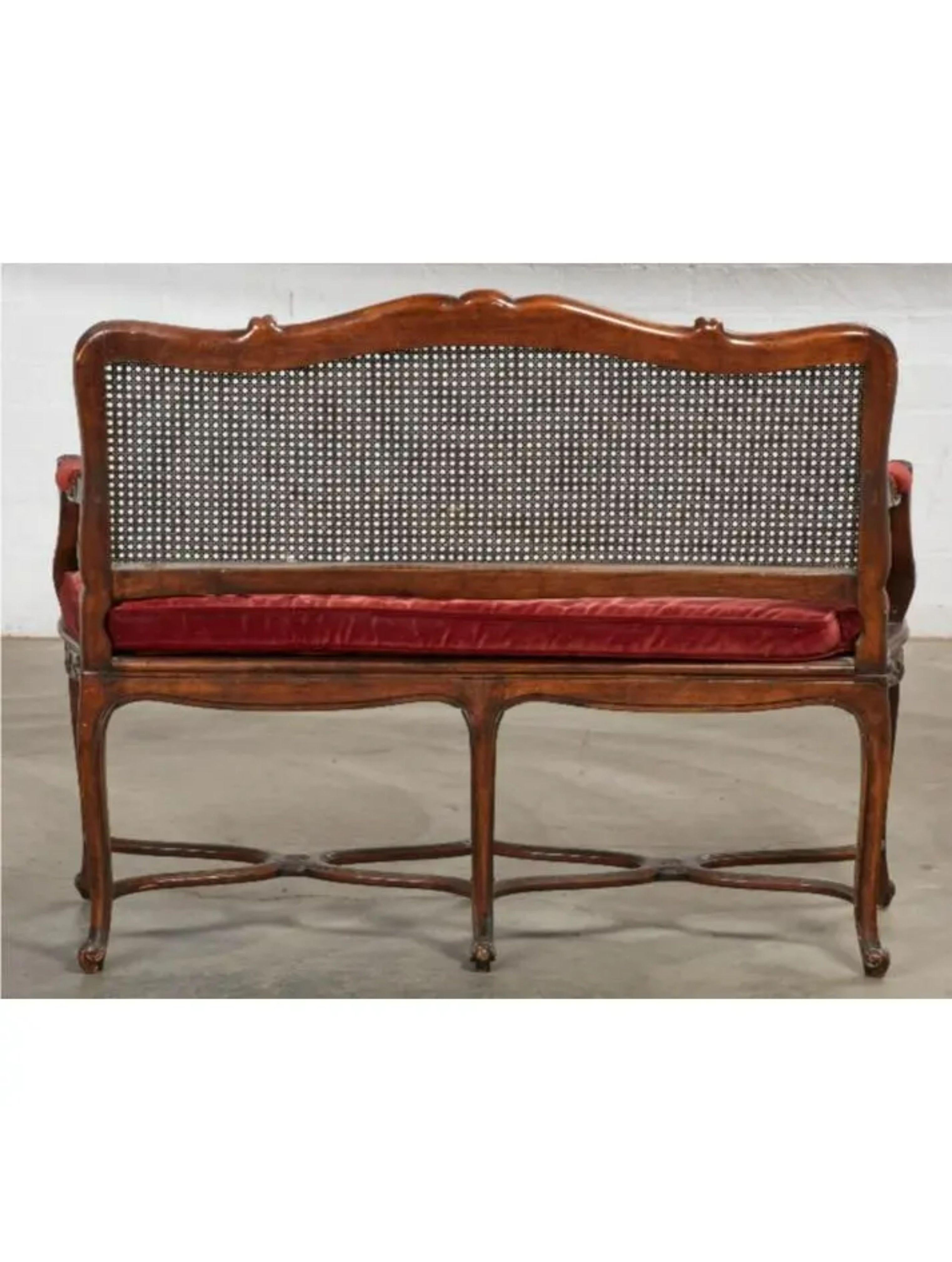 Louis XV Style French provincial carved walnut & cane seat settee. It featured a red velvet down filled cushion covering a cane seat. 

Additional information:
Materials: Caning, Walnut.
Color: Red.
Period: Early 20th century.
Styles: French