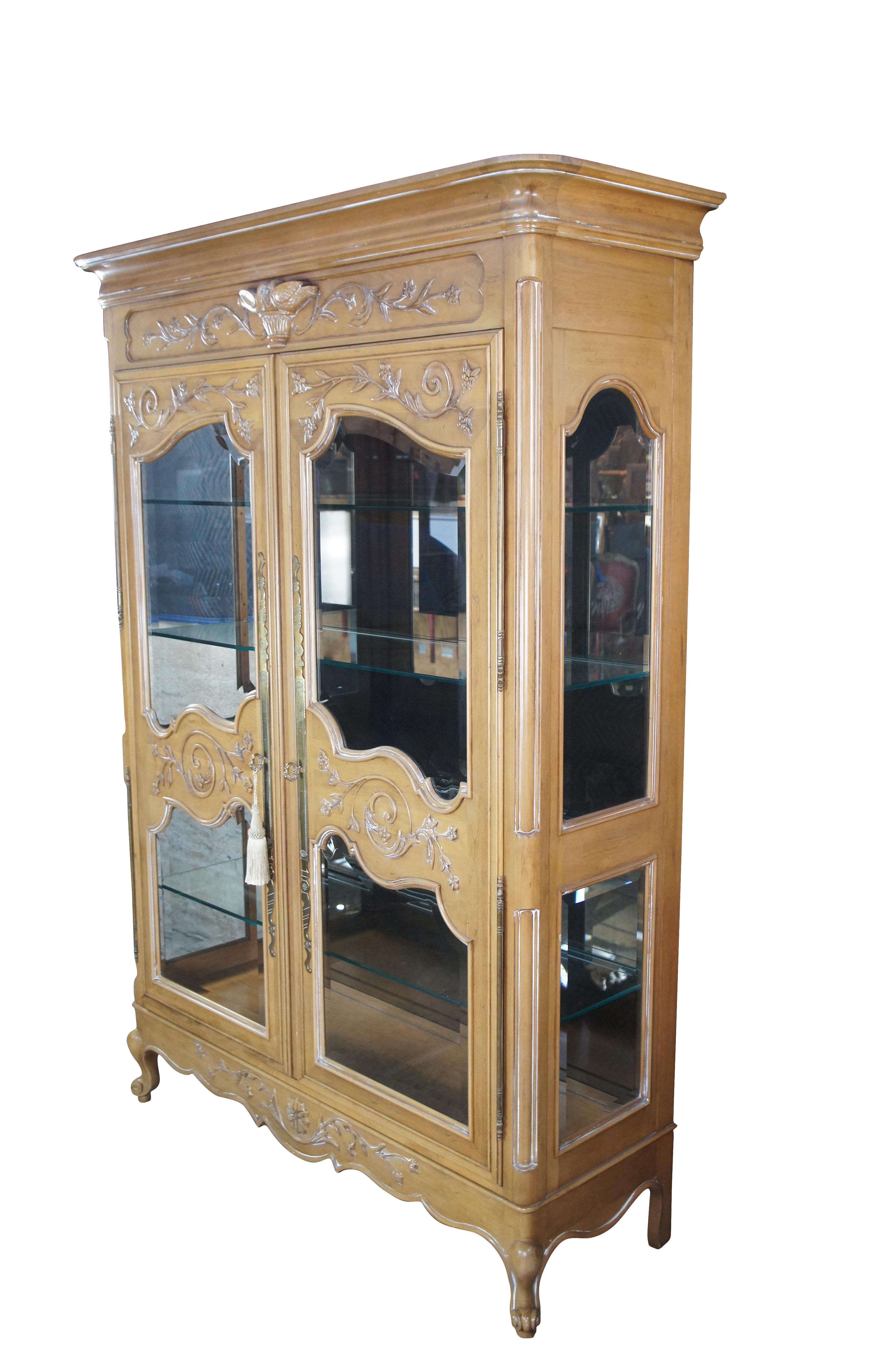 Grande et impressionnante vitrine de style Louis XV / Provincial français, vers 1990. Le cadre en bois fruitier robuste est orné de feuillages et d'oiseaux chanteurs sculptés.  L'armoire s'ouvre sur un intérieur éclairé avec un dos en miroir et