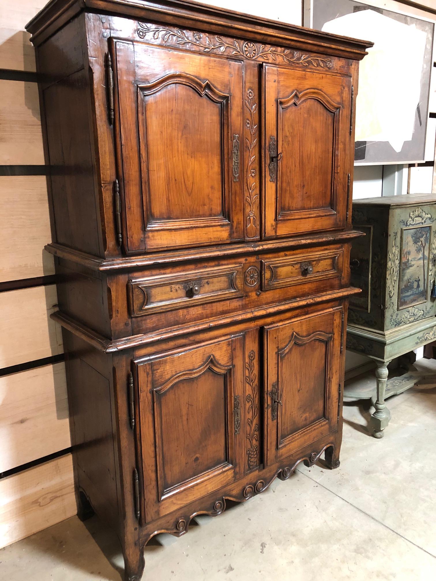 A beautiful Louis XV style French Provincial tall buffet made of deeply patinated pear wood retaining the original deep lustrous color. Four doors with shaped and molded panels and raised carved floral decoration. Two central drawers give extra