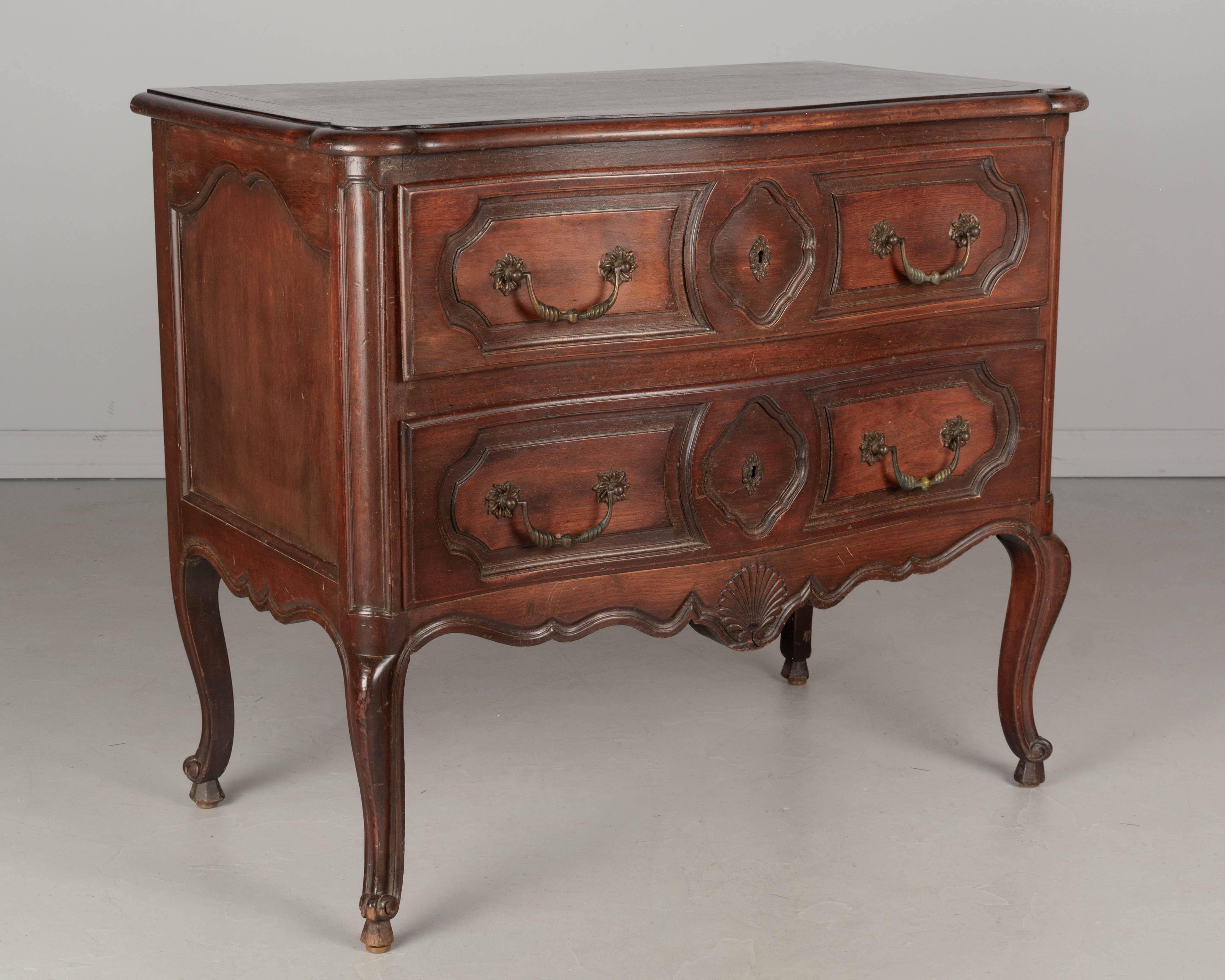 A French Louis XV style commode with serpentine front made of solid walnut with walnut veneer top and oak as a secondary wood. Two dovetailed drawers with brass hardware, no key. A nice vintage chest in good condition. Circa 1950s. Could be used for