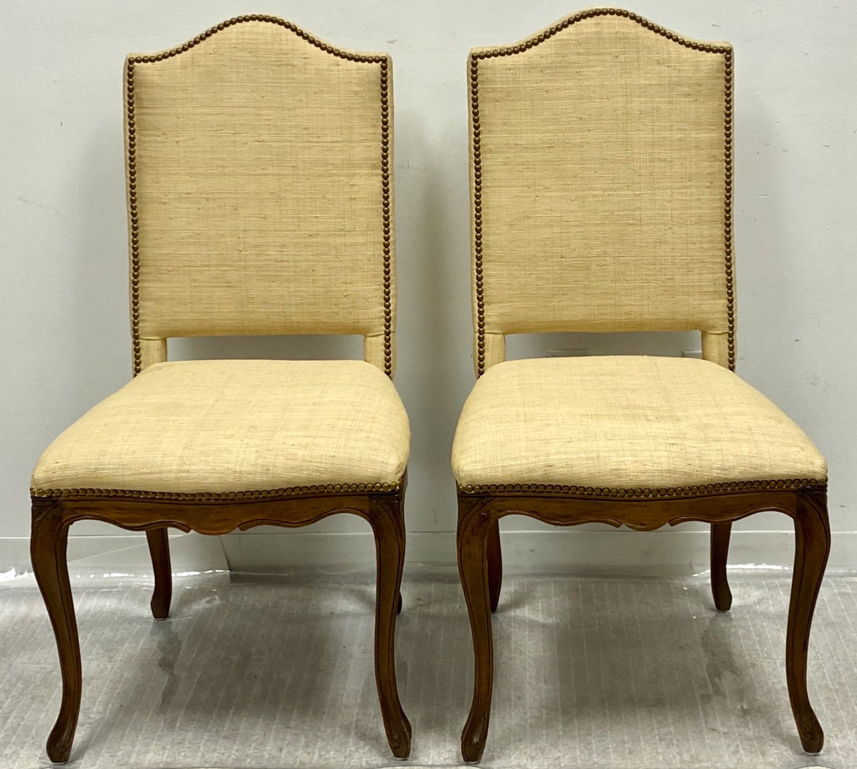 Il s'agit d'une paire de chaises d'appoint de style Louis XV, enveloppées de toile de gazon, avec des dossiers à carreaux et des têtes de clous en laiton. Elles sont attribuées à Grange et datent probablement de la fin du XXe siècle. Ils sont en