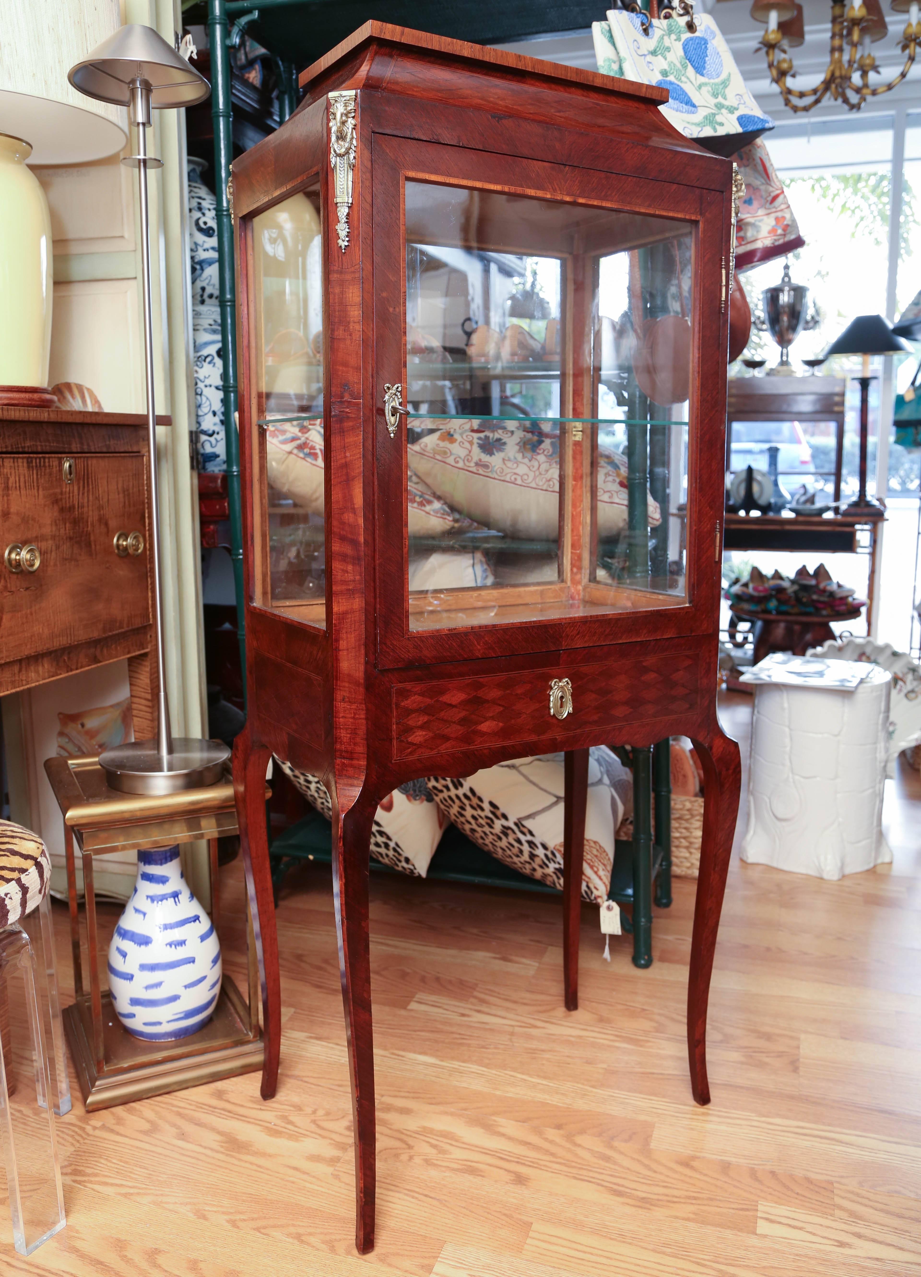 Antique French vitrine with glass on four sides. Interior has mirrored bottom shelf and one glass shelf in middle. Four corner mountings on top with ram's heads.