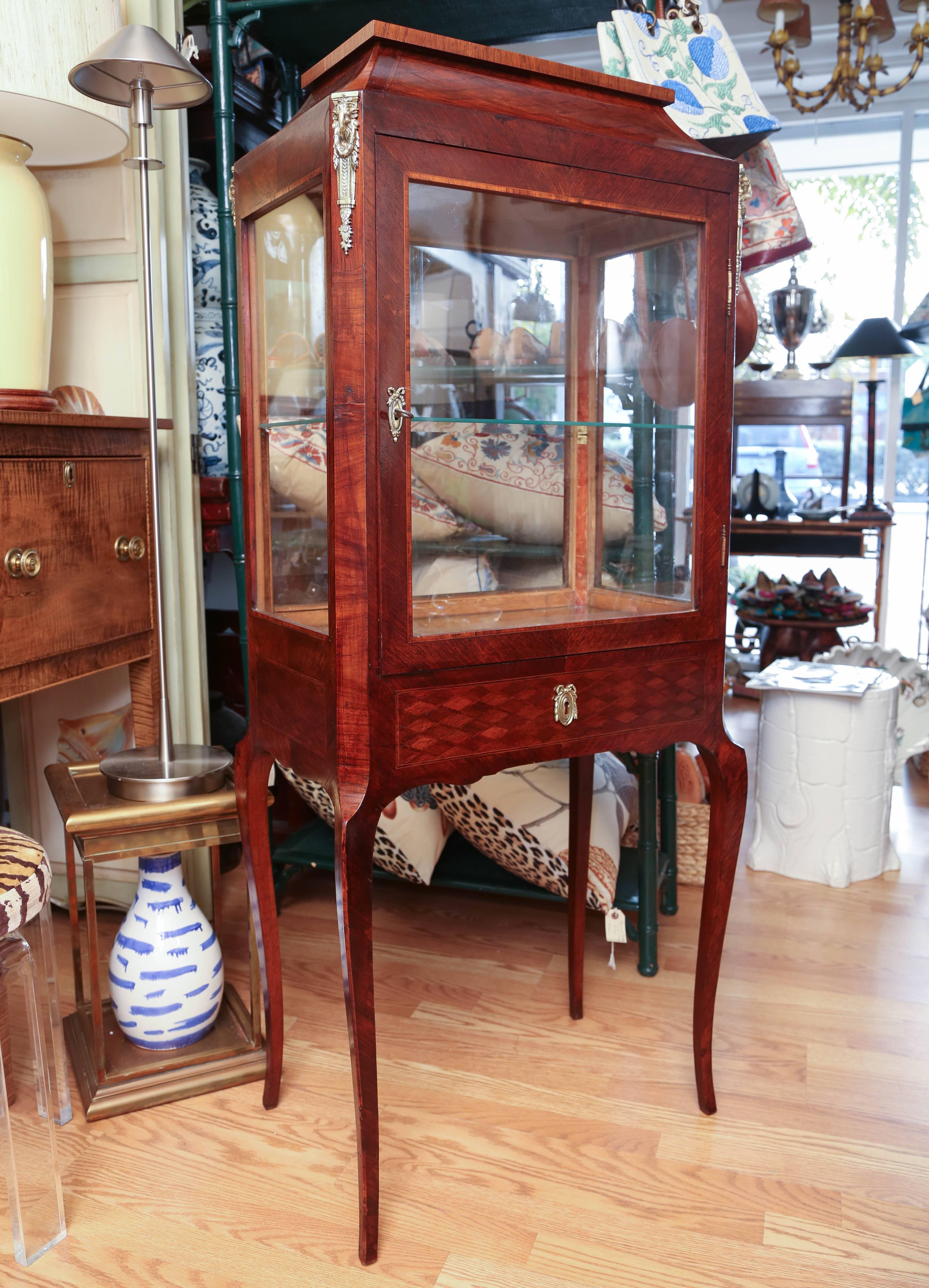 Antique French vitrine con vetro su quattro lati. L'interno è dotato di un ripiano inferiore a specchio e di un ripiano centrale in vetro. Quattro attacchi angolari sulla parte superiore con teste di ariete.
