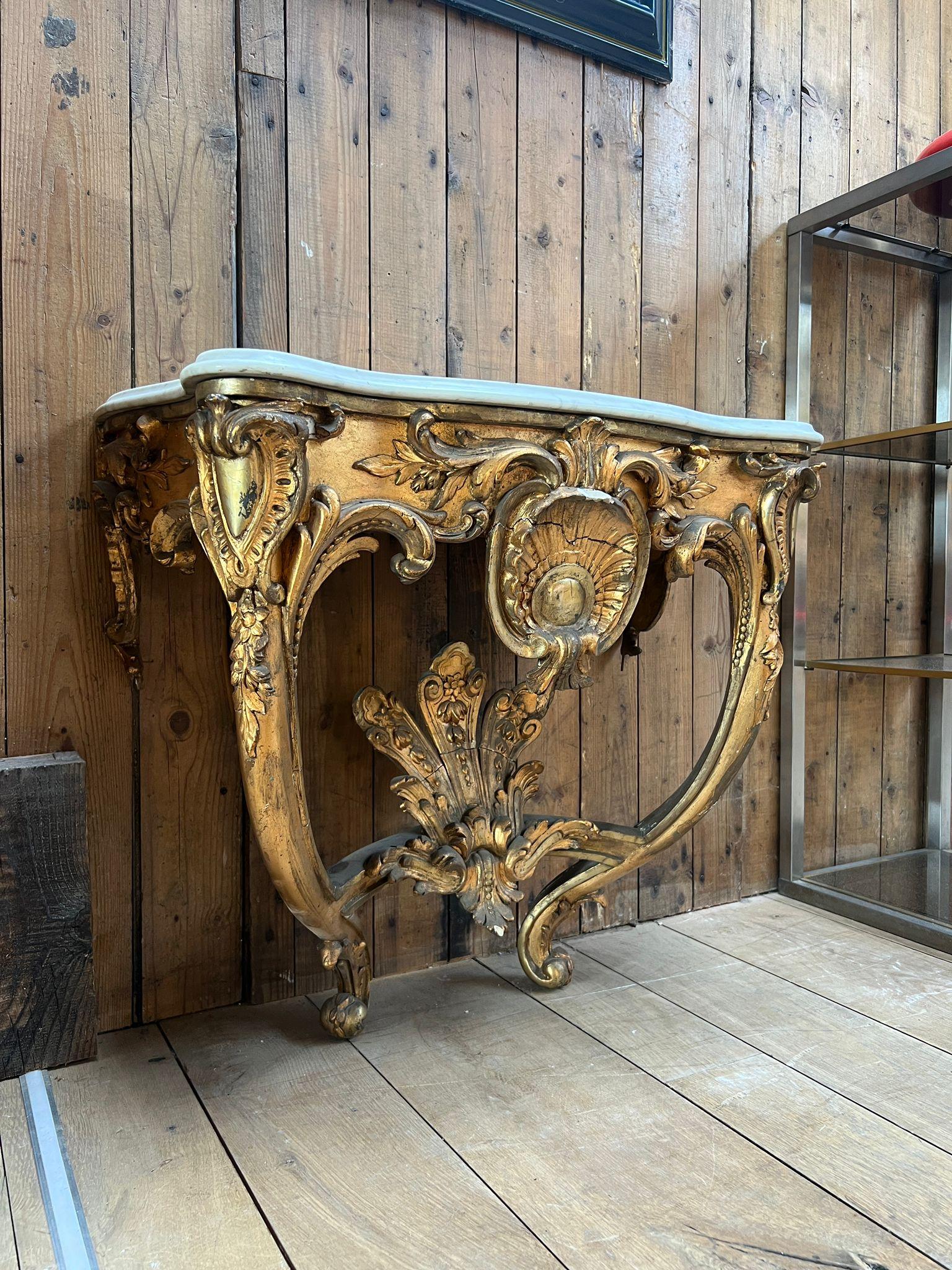 A striking 19th-century Louis XV-style console, richly hand-carved and adorned with gilded scrollwork, floral motifs, and Rococo detailing. This elegant wall-mounted console is topped with a beautifully shaped white marble slab that complements the