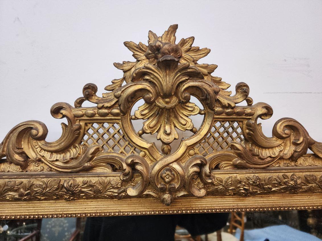 French Louis XV Style Gilded painted mirror with designs surrounding the frame and carvings at the top. 