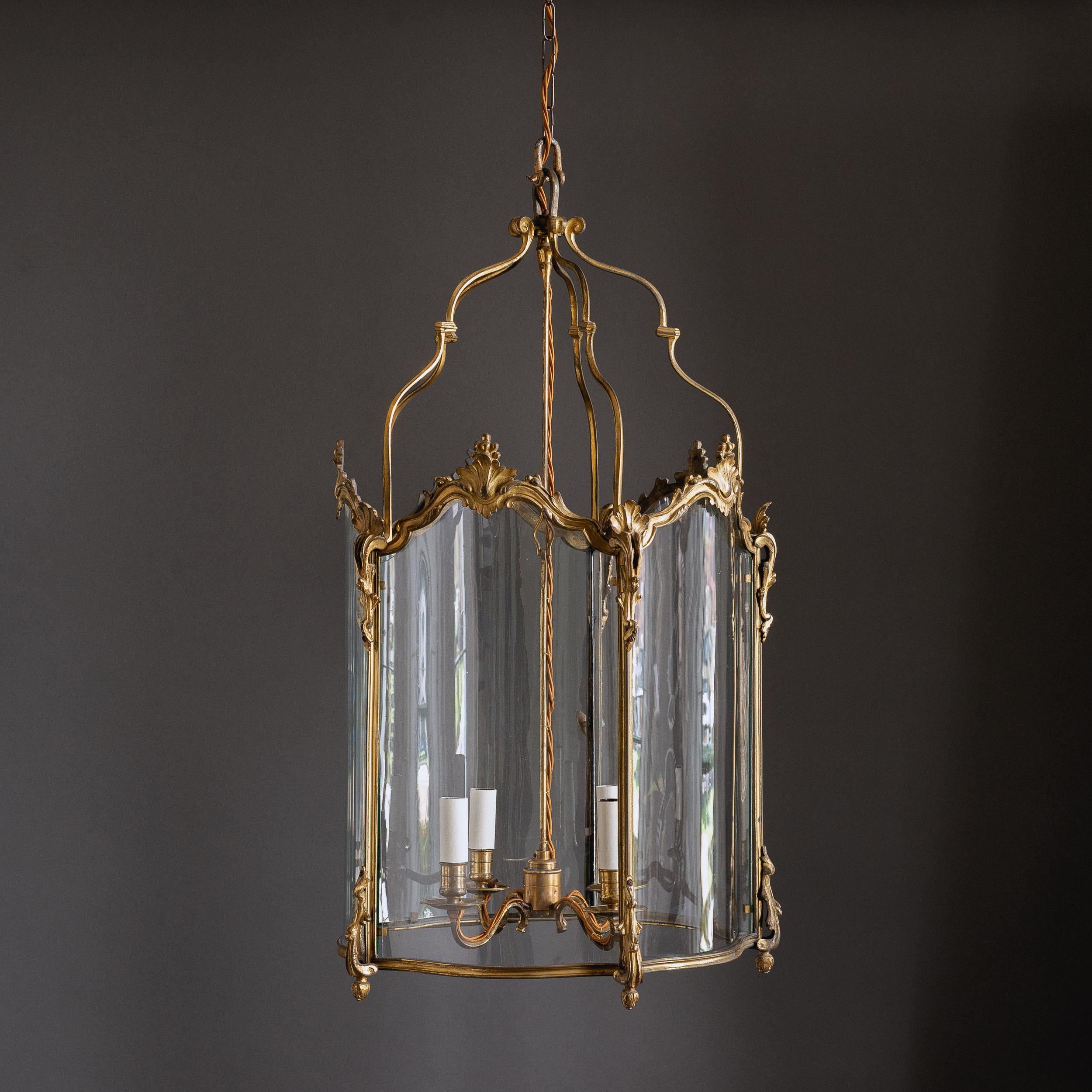A Fine Louis XV style gilt-bronze lantern, late 19th century, French,
in the Rococo manner, with serpentine glazed panels and four-light suspended chandelier within, re-wired and PAT tested. 