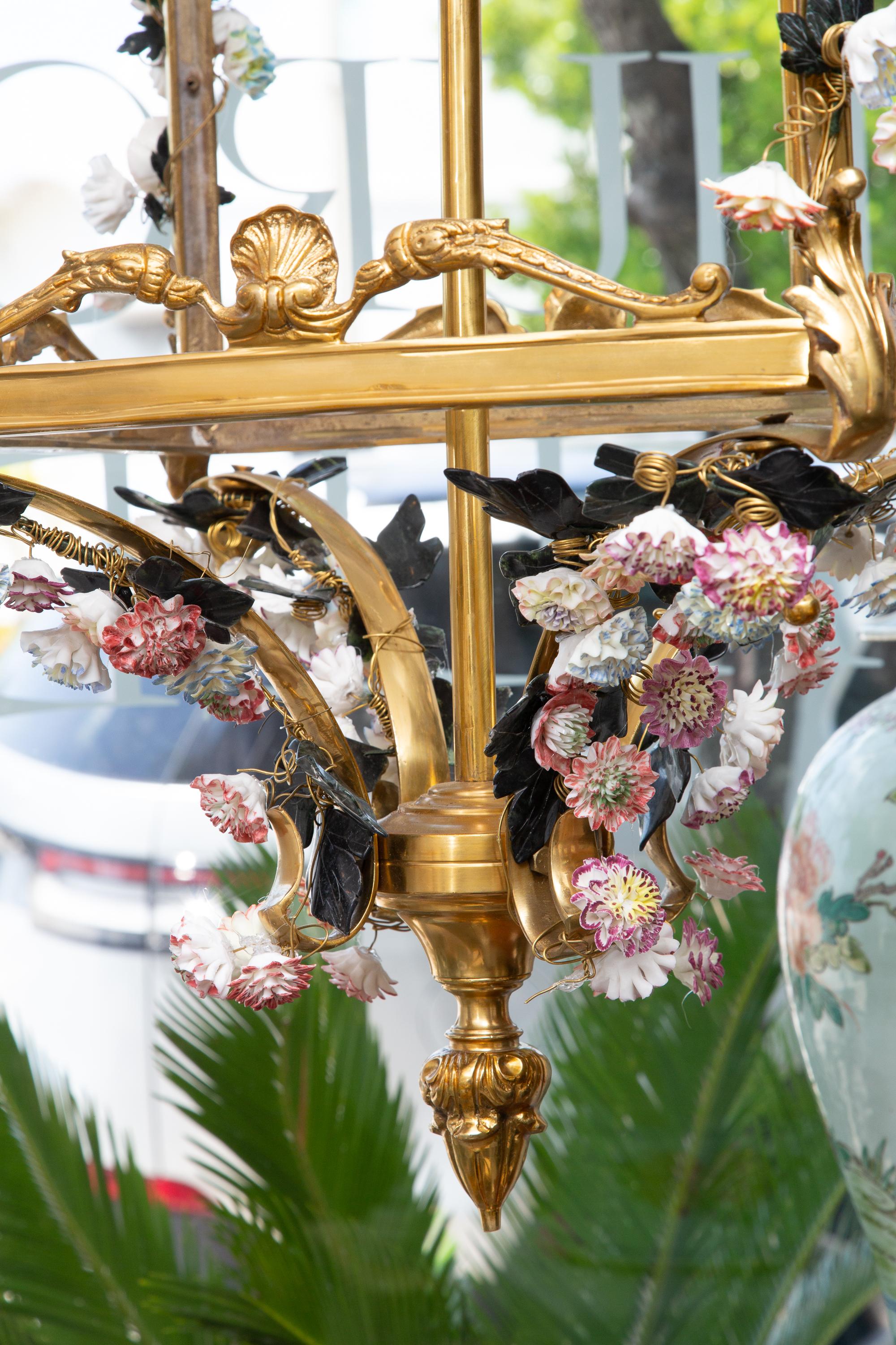 This is a spectacular Louis XV style bronze chandelier in lantern-form with varying porcelain flower heads distributed over-all.