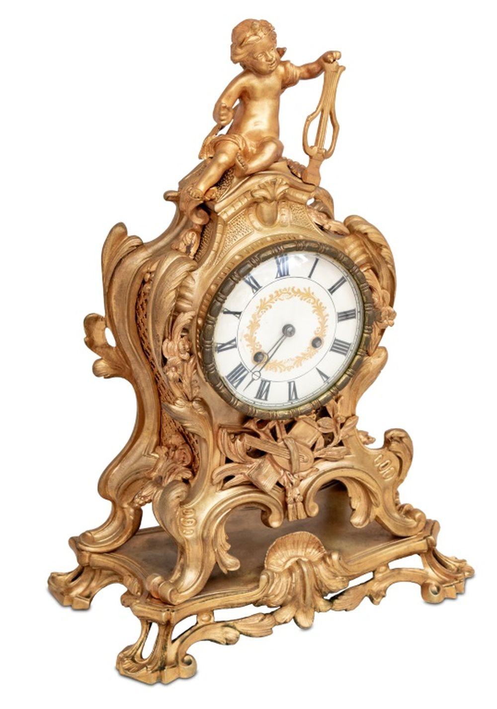 Louis XV Style Gilt Bronze Mantel Clock, late 19th century, the circular dial surmounted by a cherub playing a harp, the movement strike on bell, on an integral scrolled base. 18.5