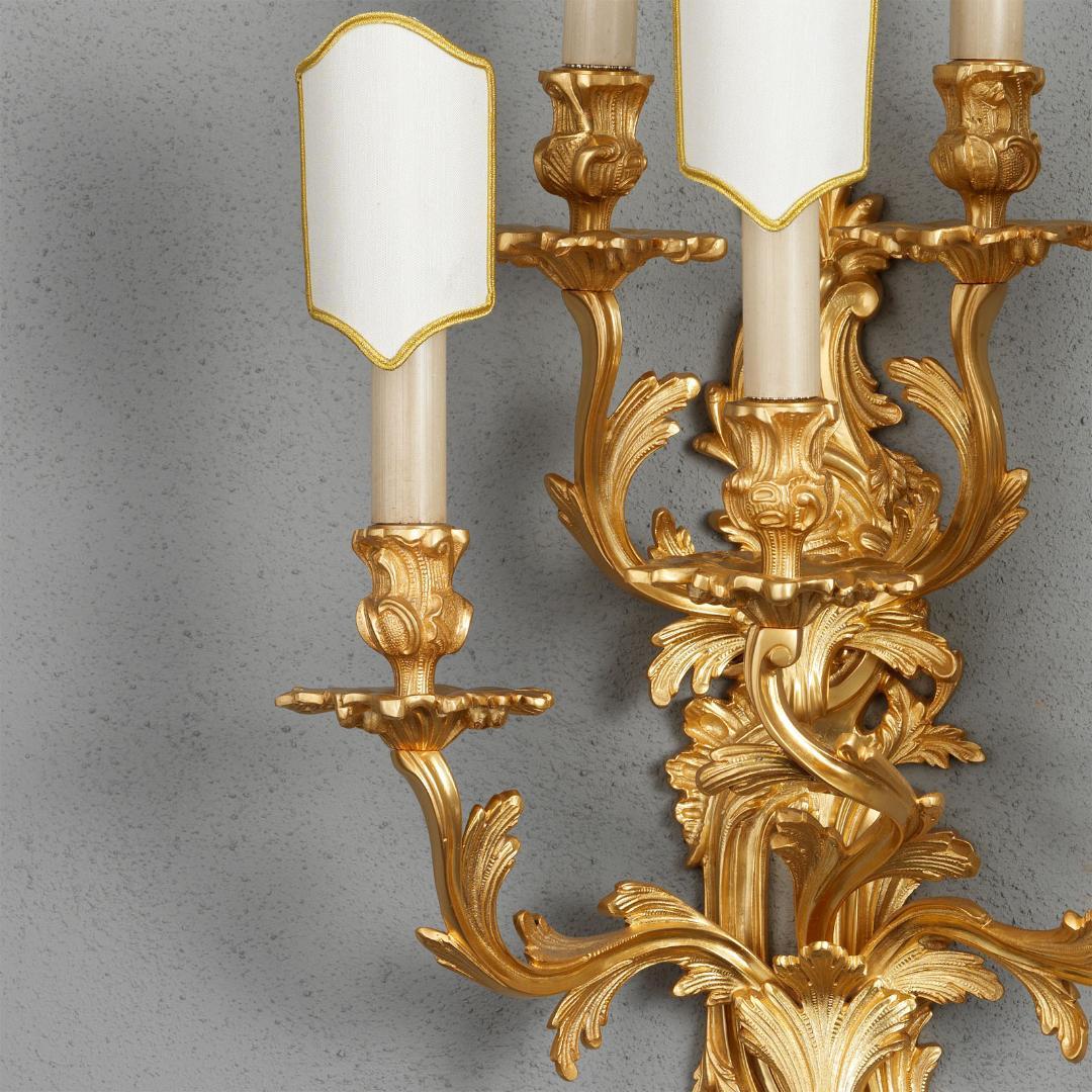 Este aplique de pared de bronce dorado estilo Luis XV de Gherardo Degli Albizzi está bellamente fundido a la manera tradicional con todo el suntuoso movimiento del periodo rococó, tiene cinco brazos que salen de la placa y están adornados con hojas