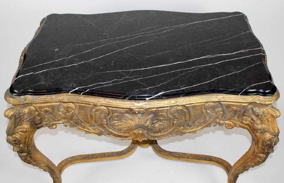 A Louis XV style gilt console table with marble top. The black serpentine-cut marble top flows gracefully over the conforming gilt wood console table base. The scalloped apron features an open-work rococo shell as well as acanthus leaf and foliate